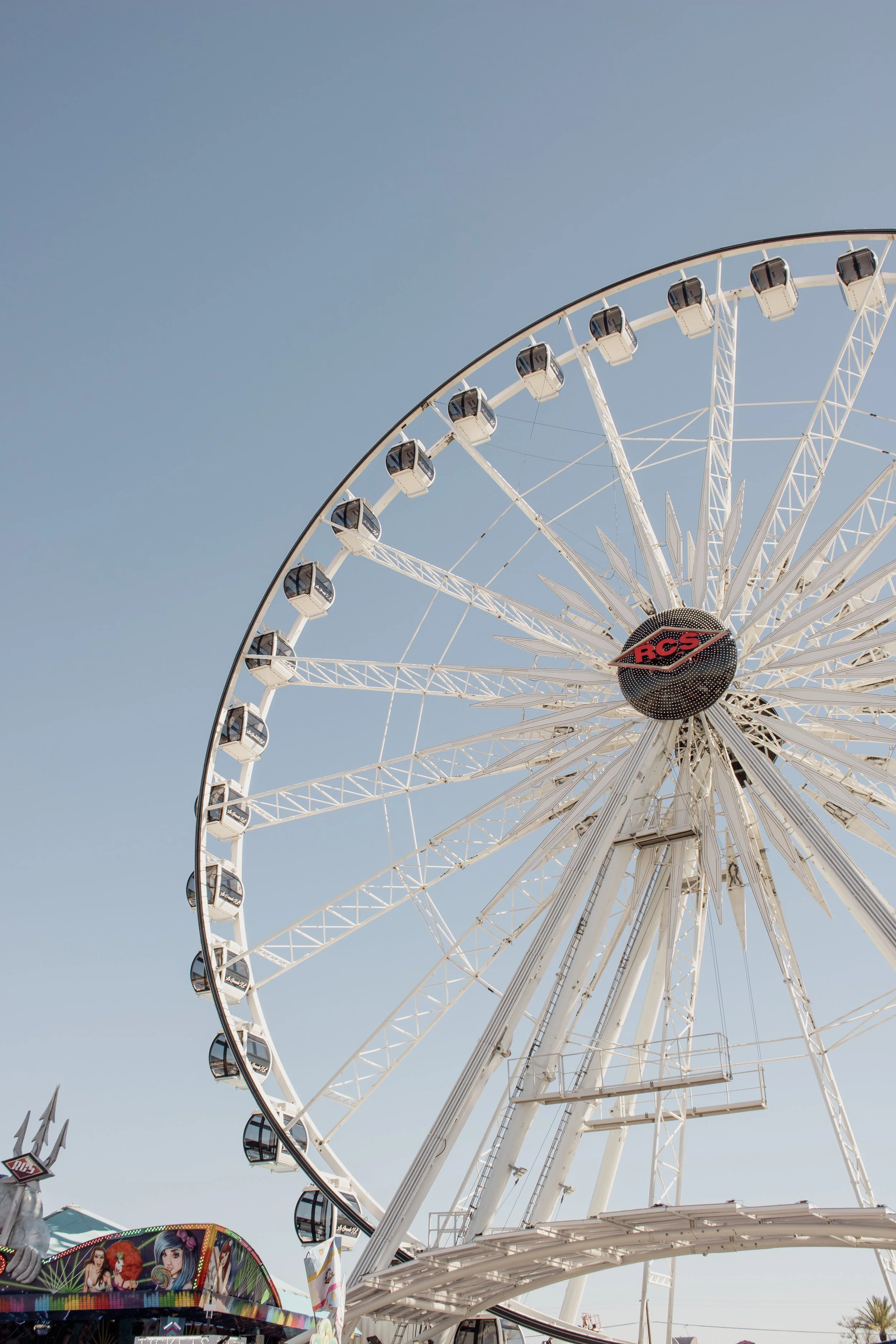 A large amusement park Ferris wheel with enclosed cabins against a clear blue sky.