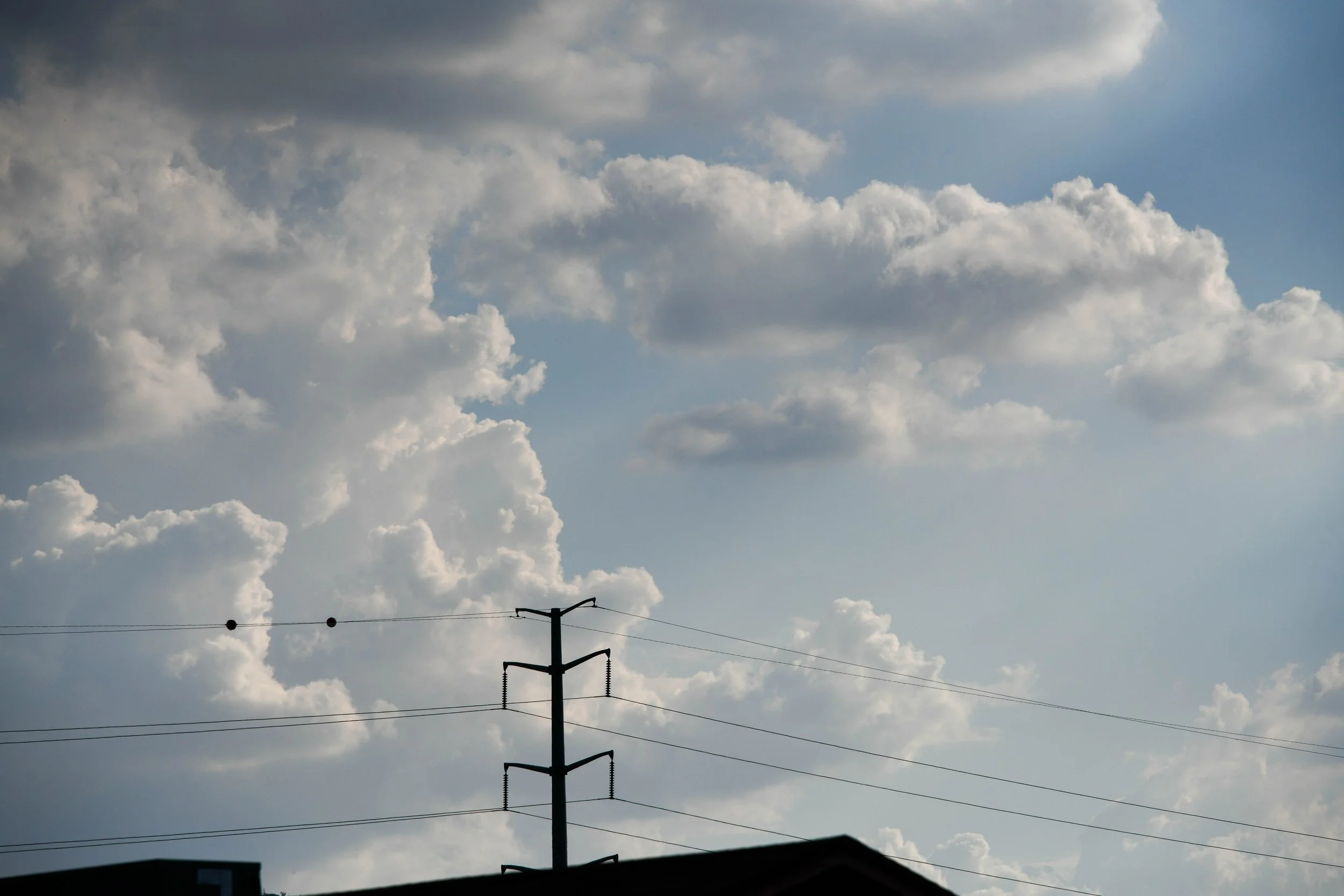 A cloudy sky with a utility pole and power lines visible in the foreground.