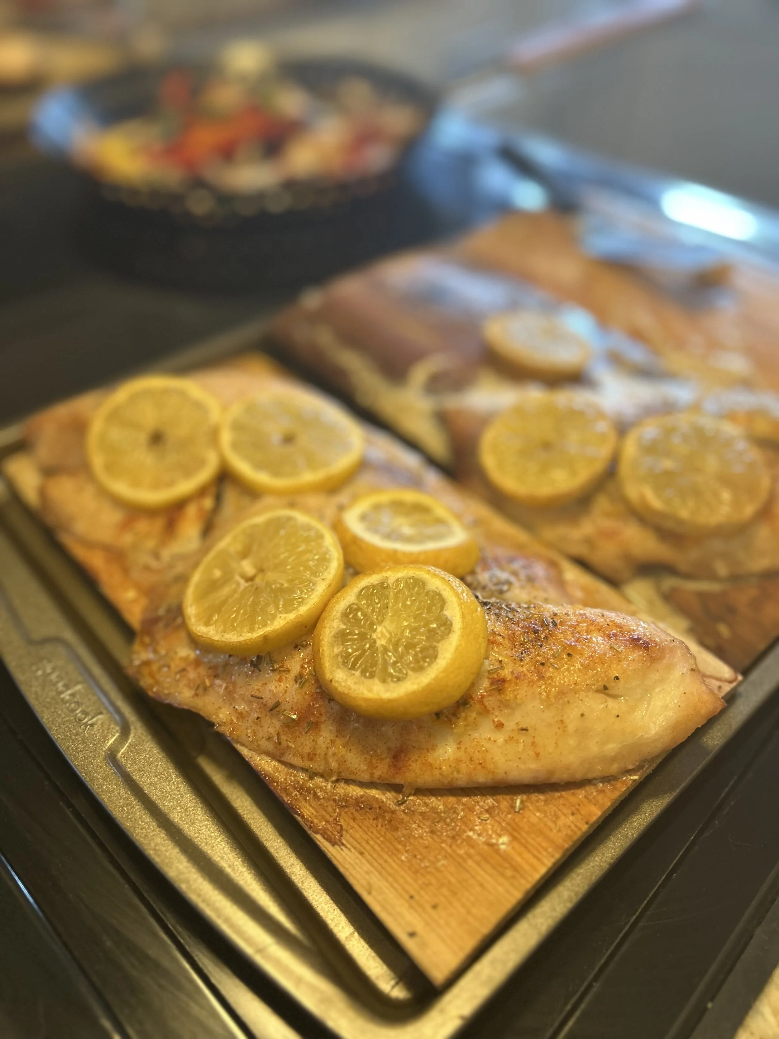 Baked salmon fillet topped with lemon slices on a baking tray.