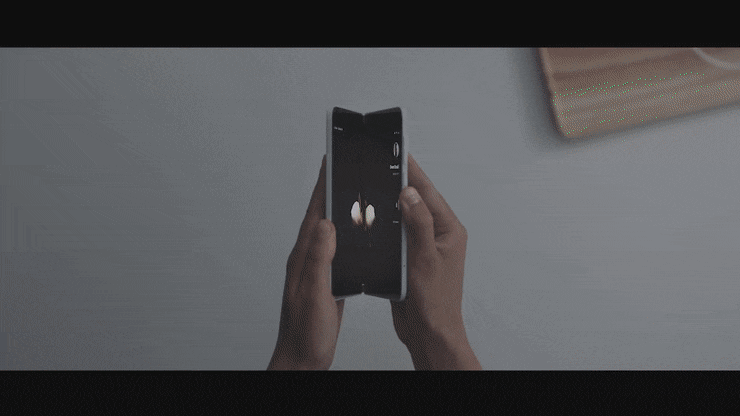 Person taking a photo of a butterfly with a smartphone on a gray surface.