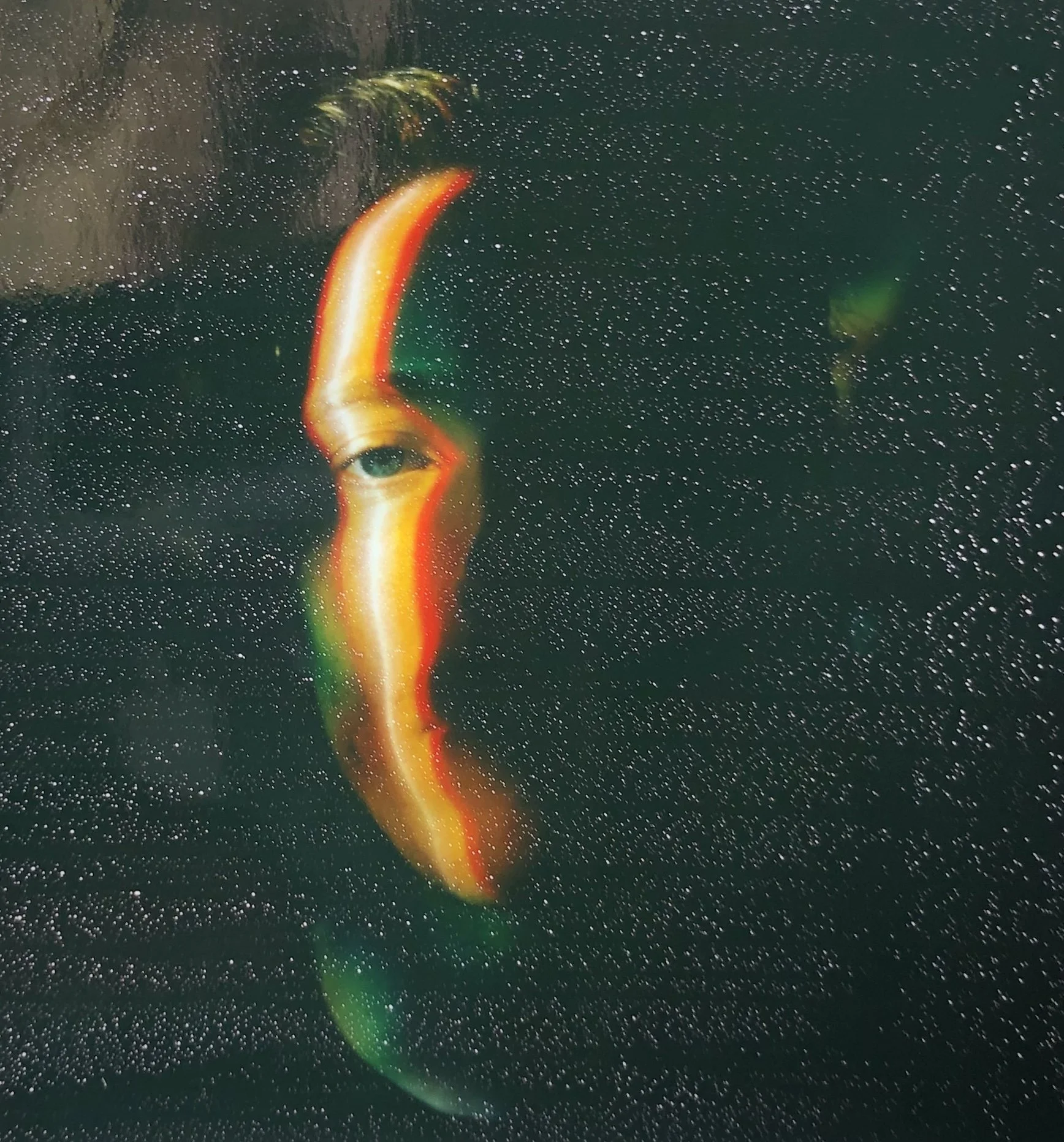 A glowing clownfish with vibrant orange and white markings, swimming in dark water with bubbles.