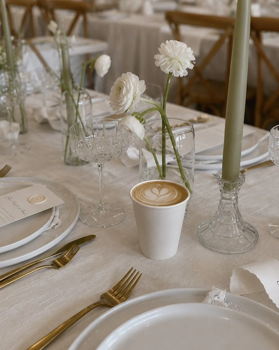 Barista pouring heart latte art into a cappuccino at a wedding coffee bar
