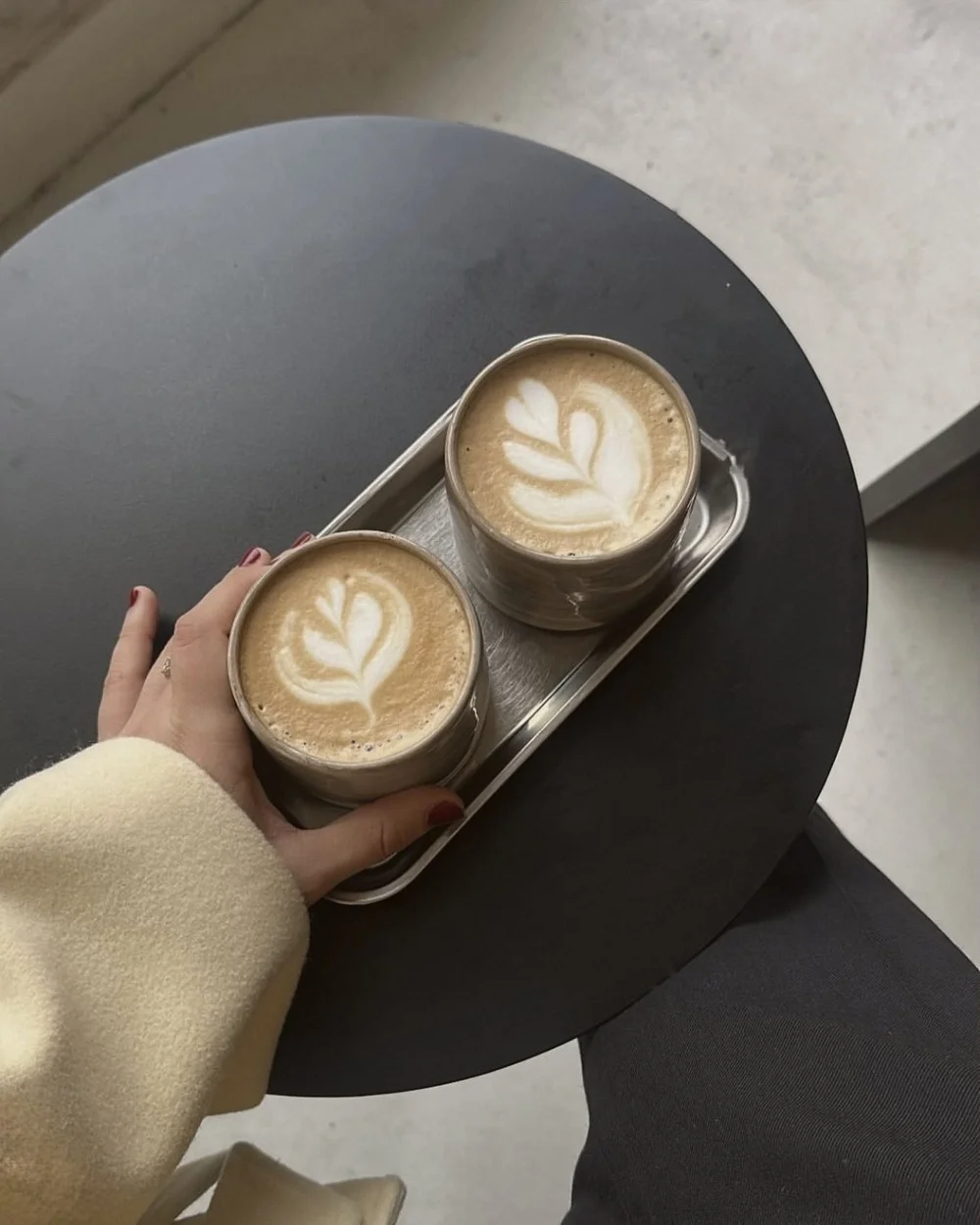 Two lattes with rosetta latte art served on a tray for the couple