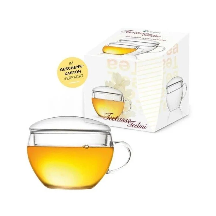 Chávena de vidro Creano com chá e tampa, apresentada junto da embalagem do produto.