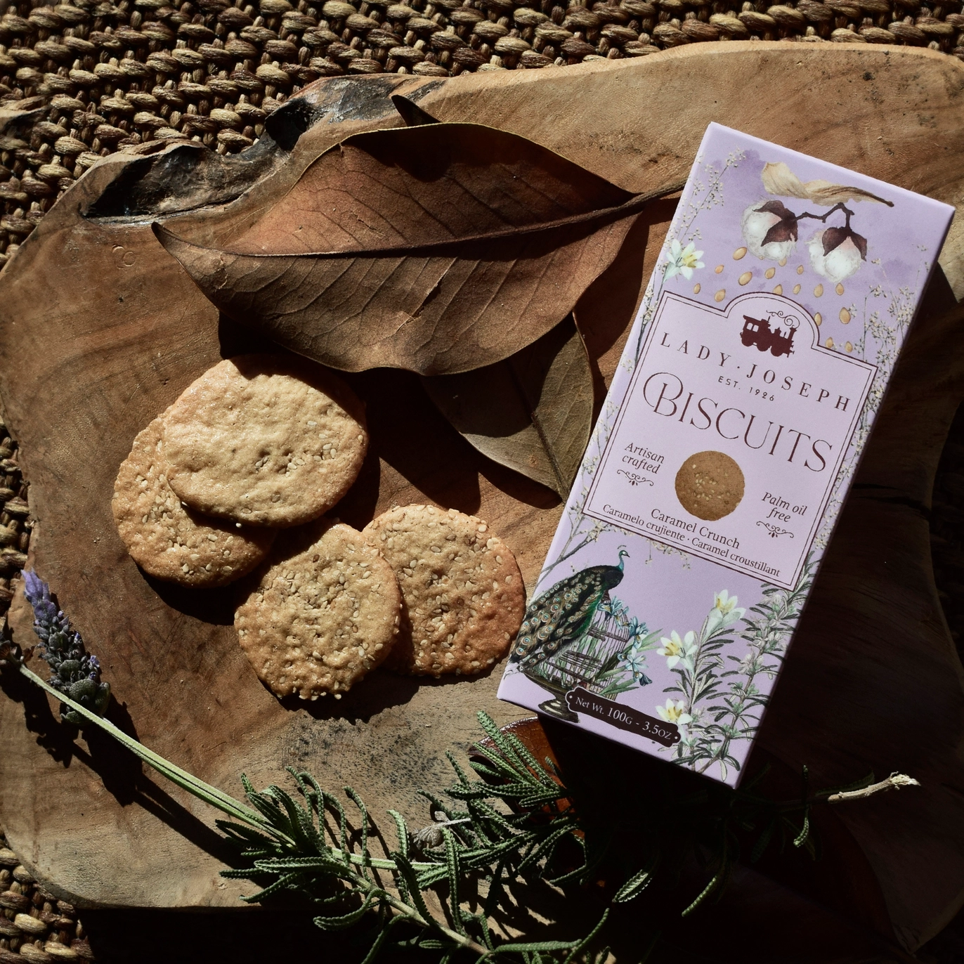 Biscoitos de Caramelo e Sésamo Lady Joseph sobre uma base de madeira, ao lado da embalagem lilás.
