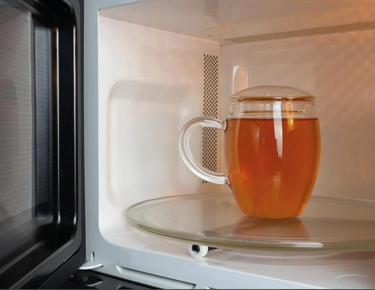 Caneca de vidro com chá no interior de um micro-ondas.