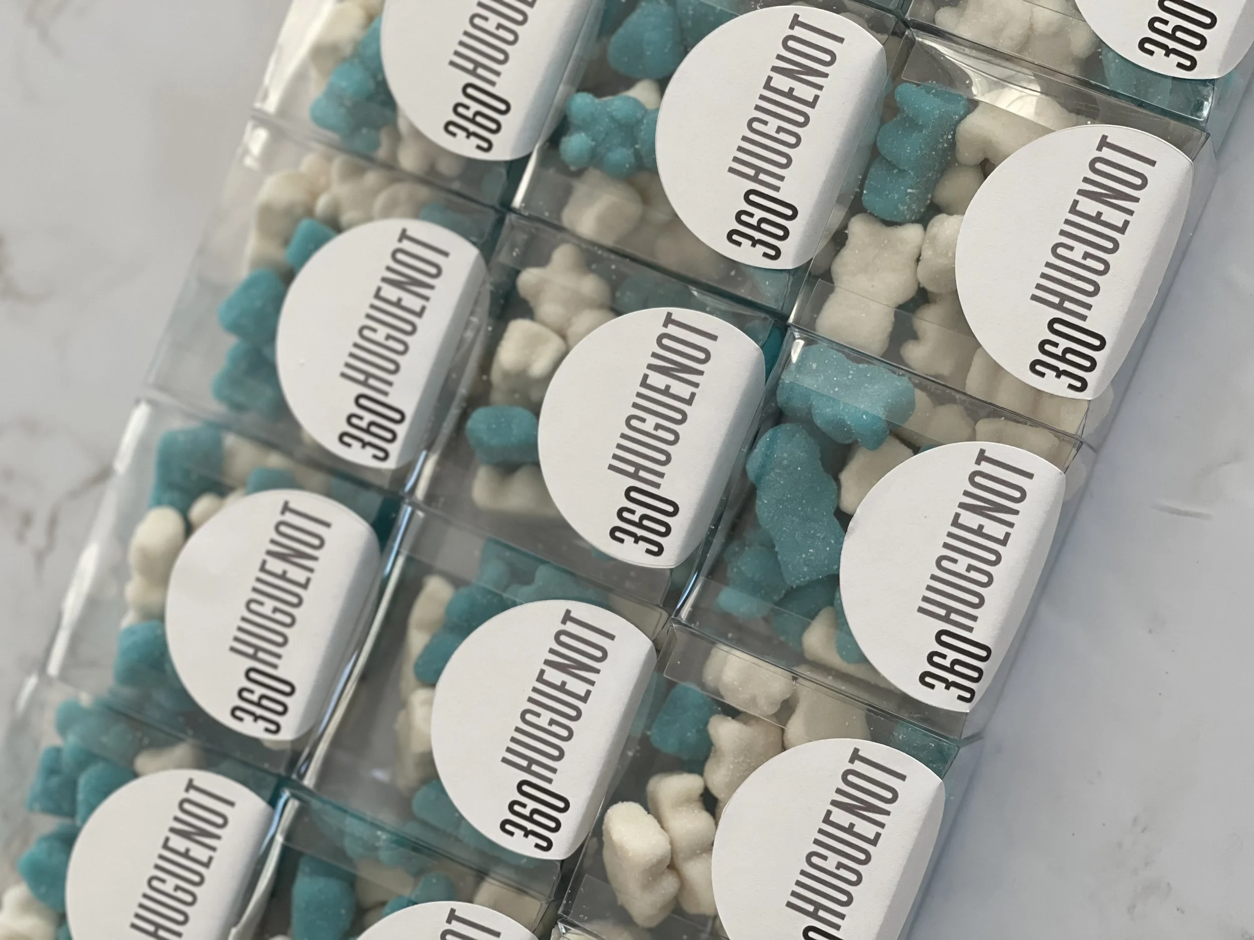 Multiple clear plastic containers filled with blue and white gummy candies shaped like bears. Each container has a white round label with the words '360GOUT' in bold black text.