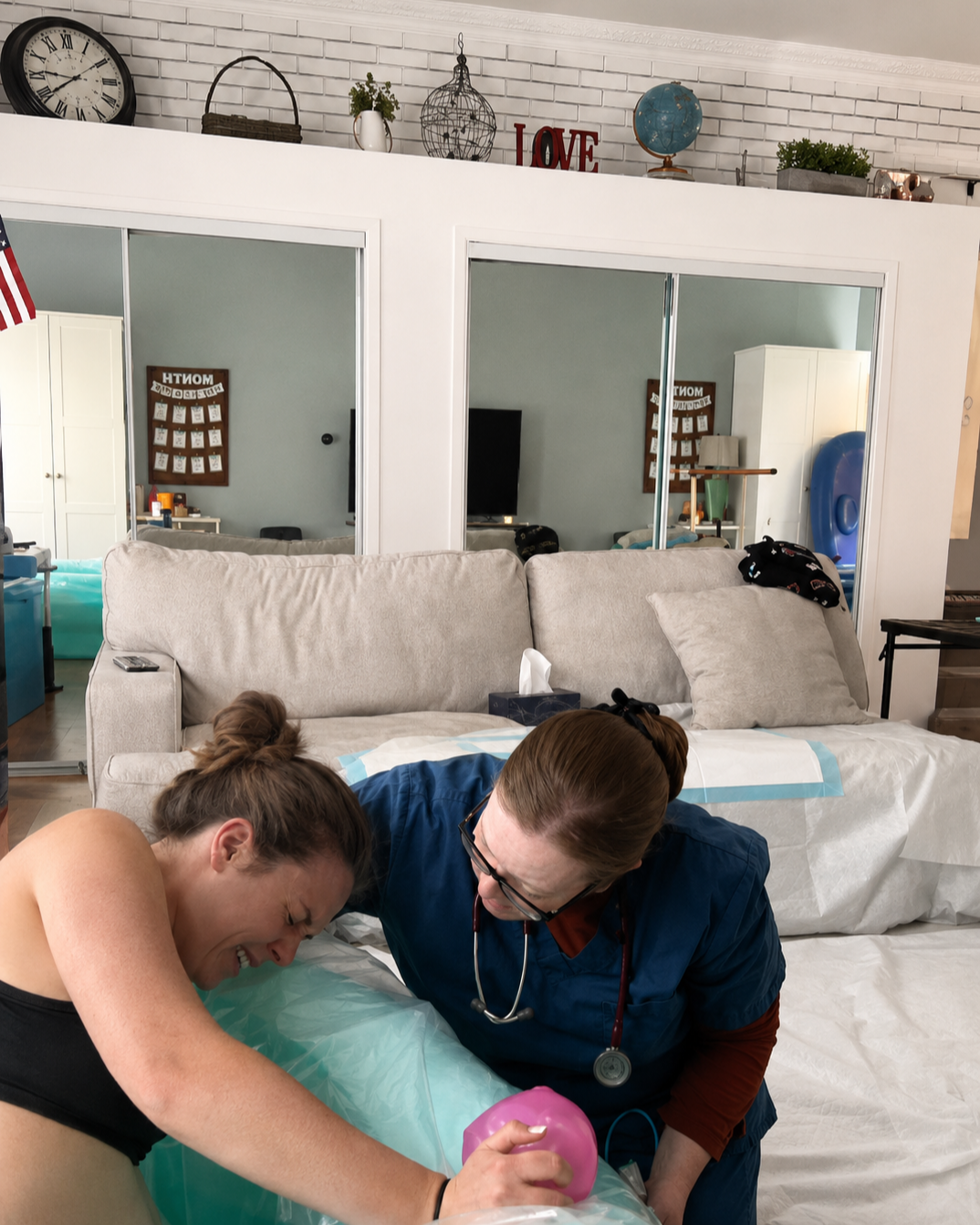 A woman and nurse laughing during a medical procedure in a room with a white couch, tissue box, wall clock, and decorative items on a white brick wall.