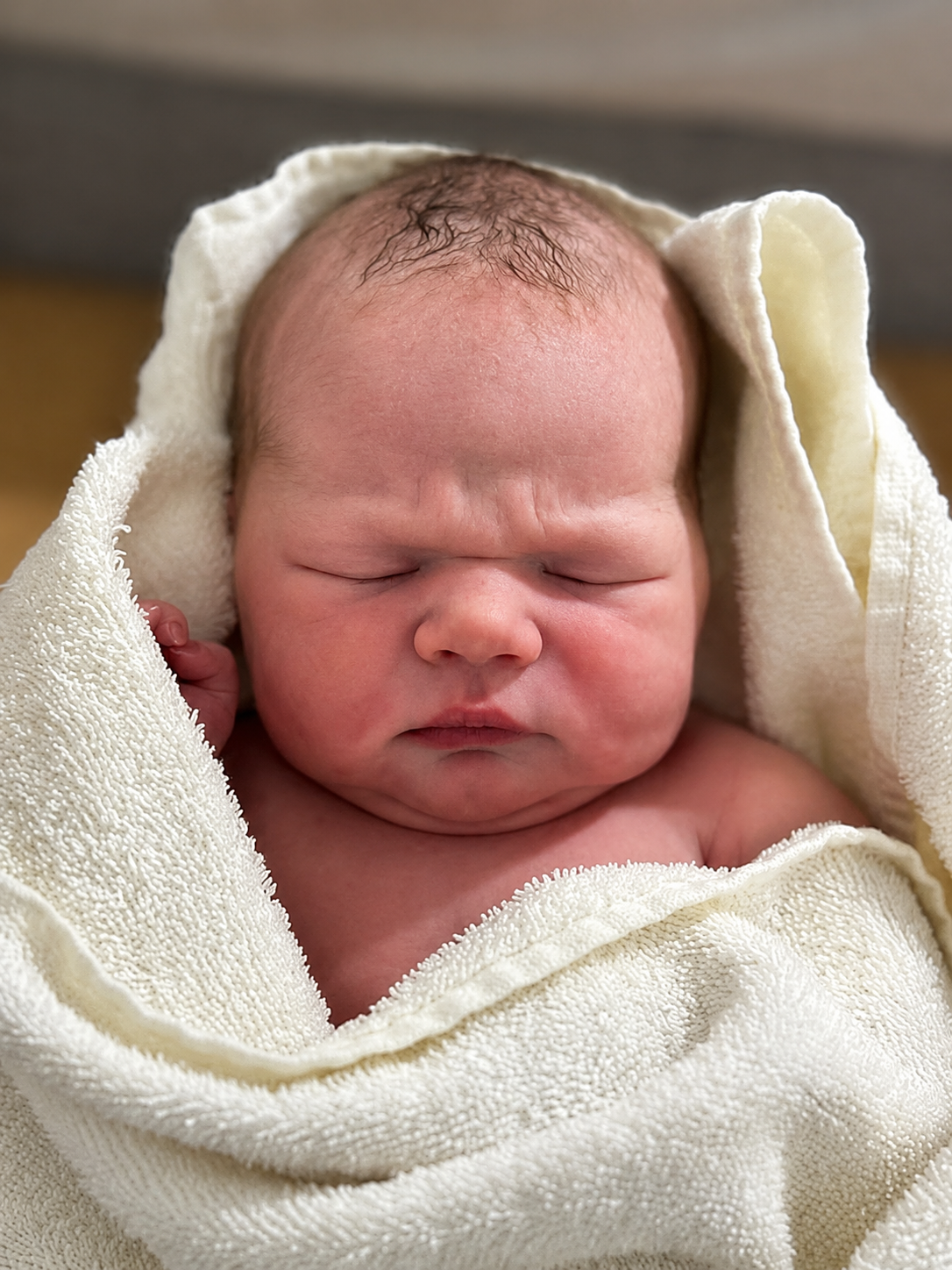 A sleeping newborn baby wrapped in a cream-colored towel.