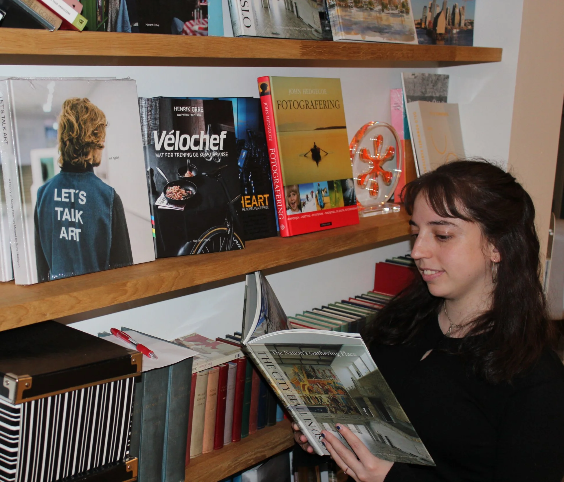 Person reading a book on art and history in a bookstore with shelves filled with various books.