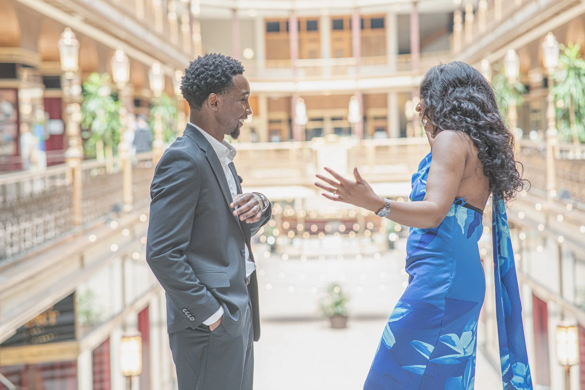 A man and woman engaging in conversation inside a shopping mall or hotel atrium.