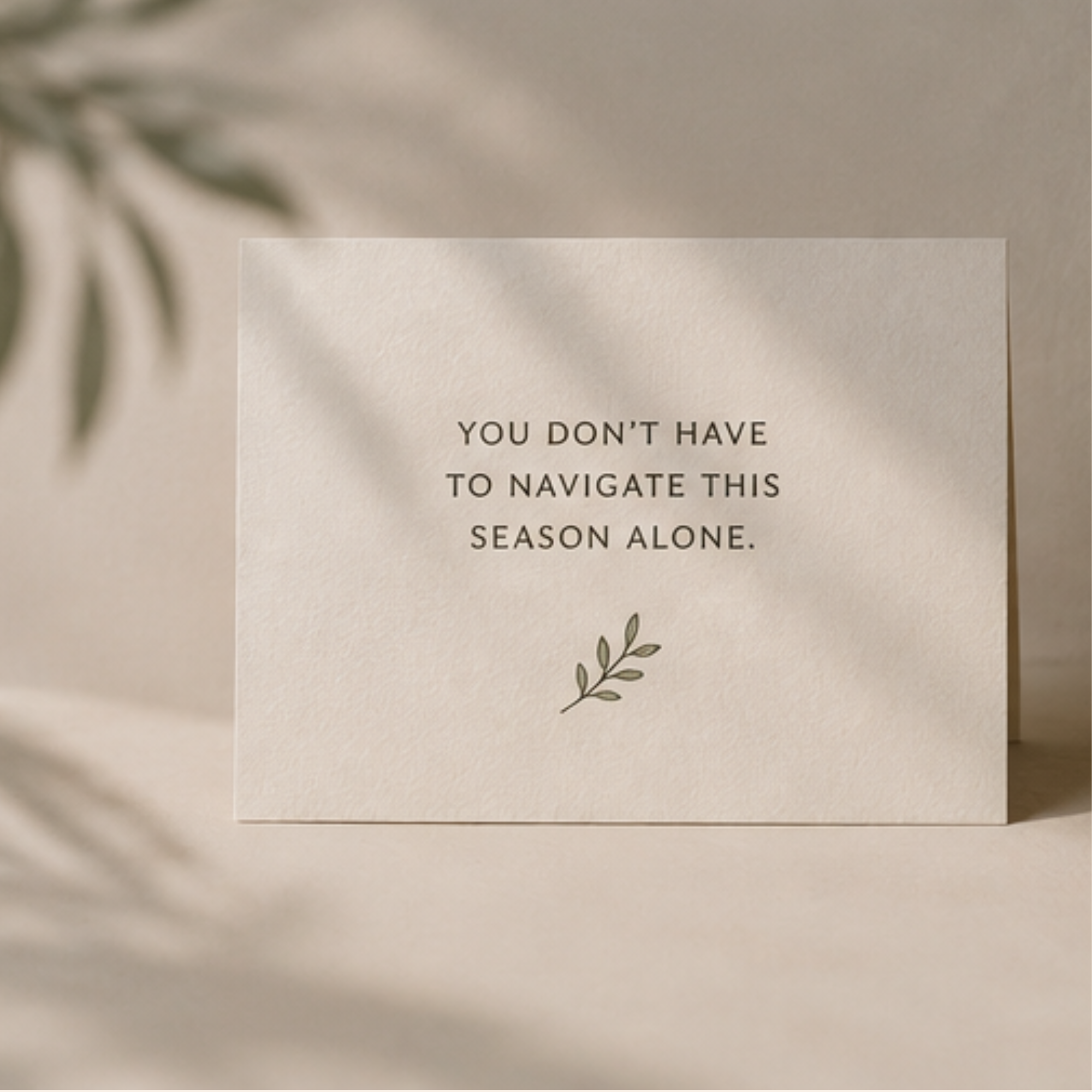Minimal cream card with the message “You don’t have to navigate this season alone” beside a small botanical illustration, representing emotional support and connection.