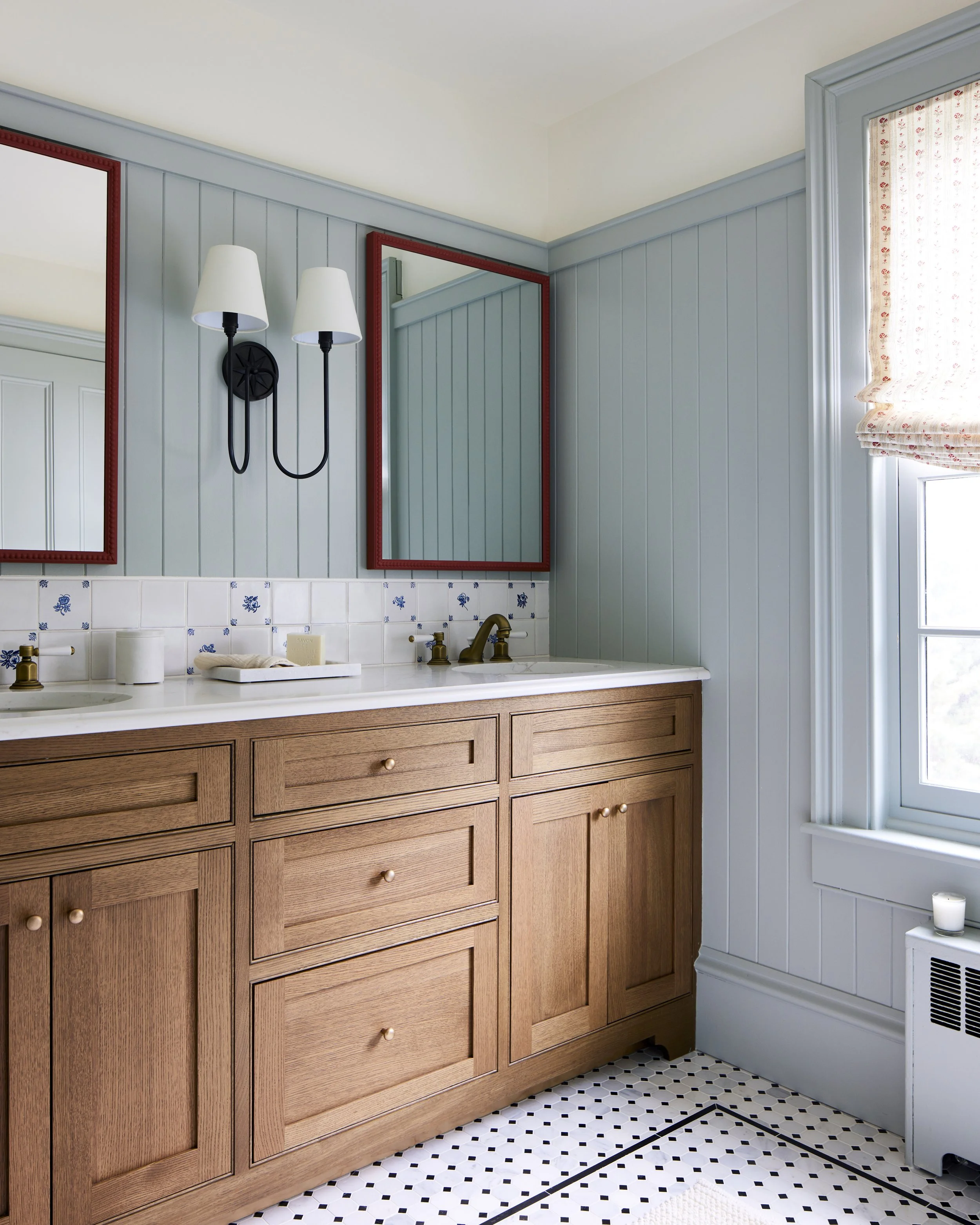 bathroom with blue walls, wood cabinetry, and red mirror