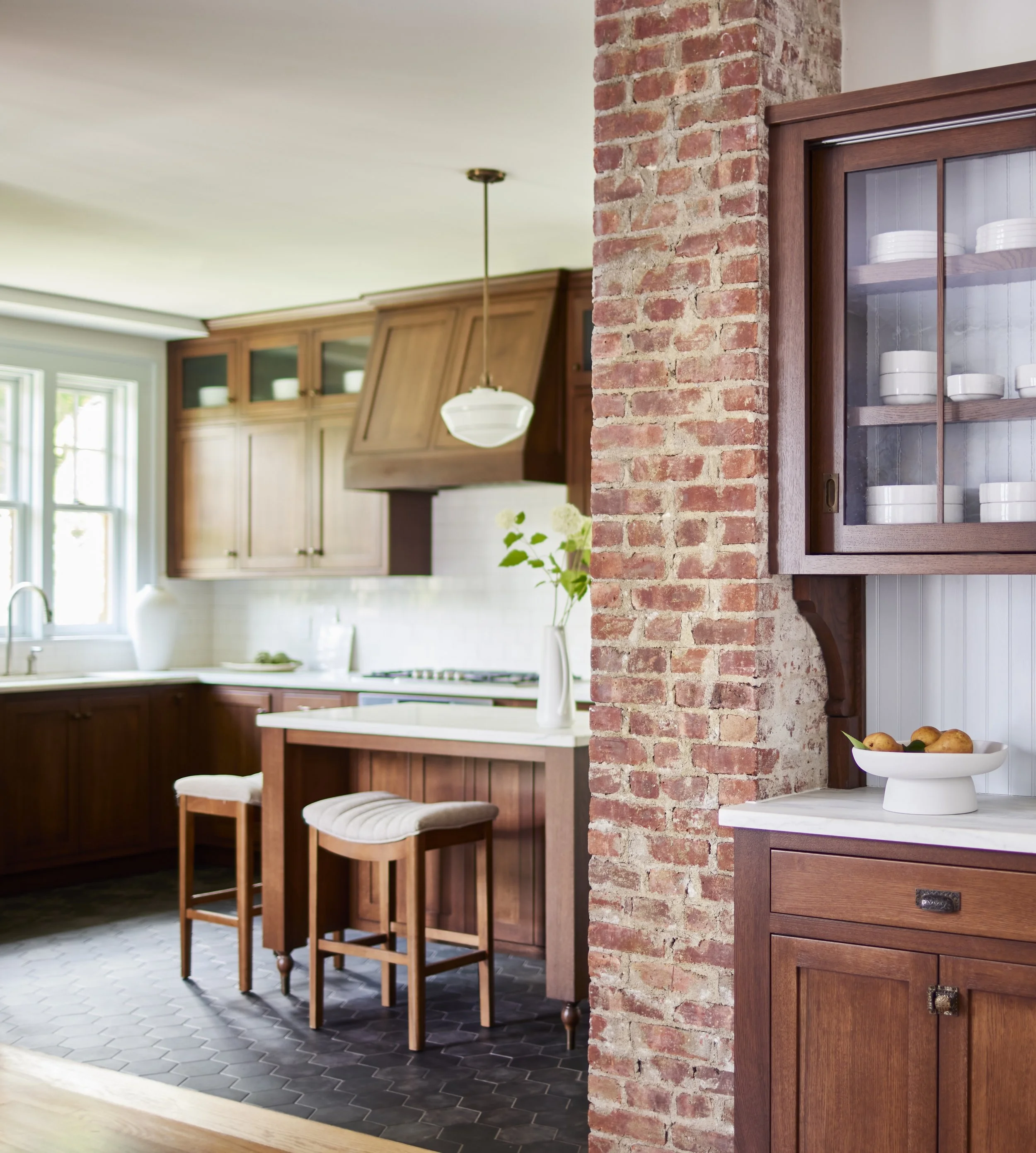 close up of display cabinet and exposed brick with shot of custom dark wood kitchen in background