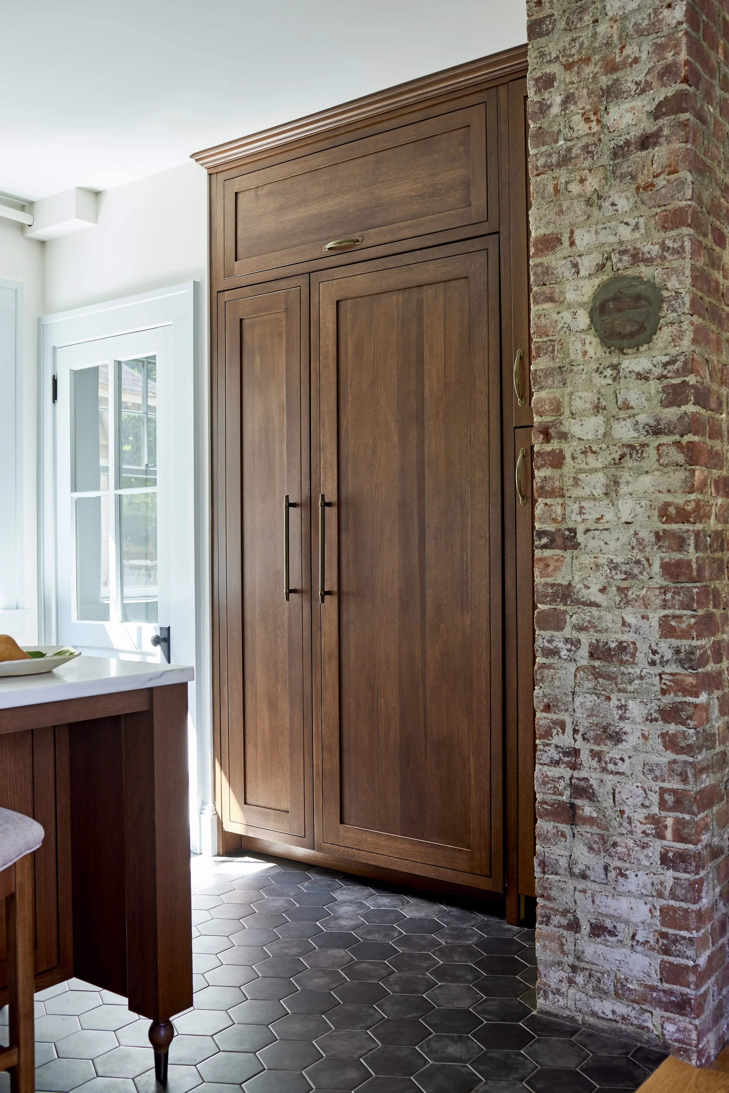 dark wood kitchen pantry with exposed brick on bordering wall