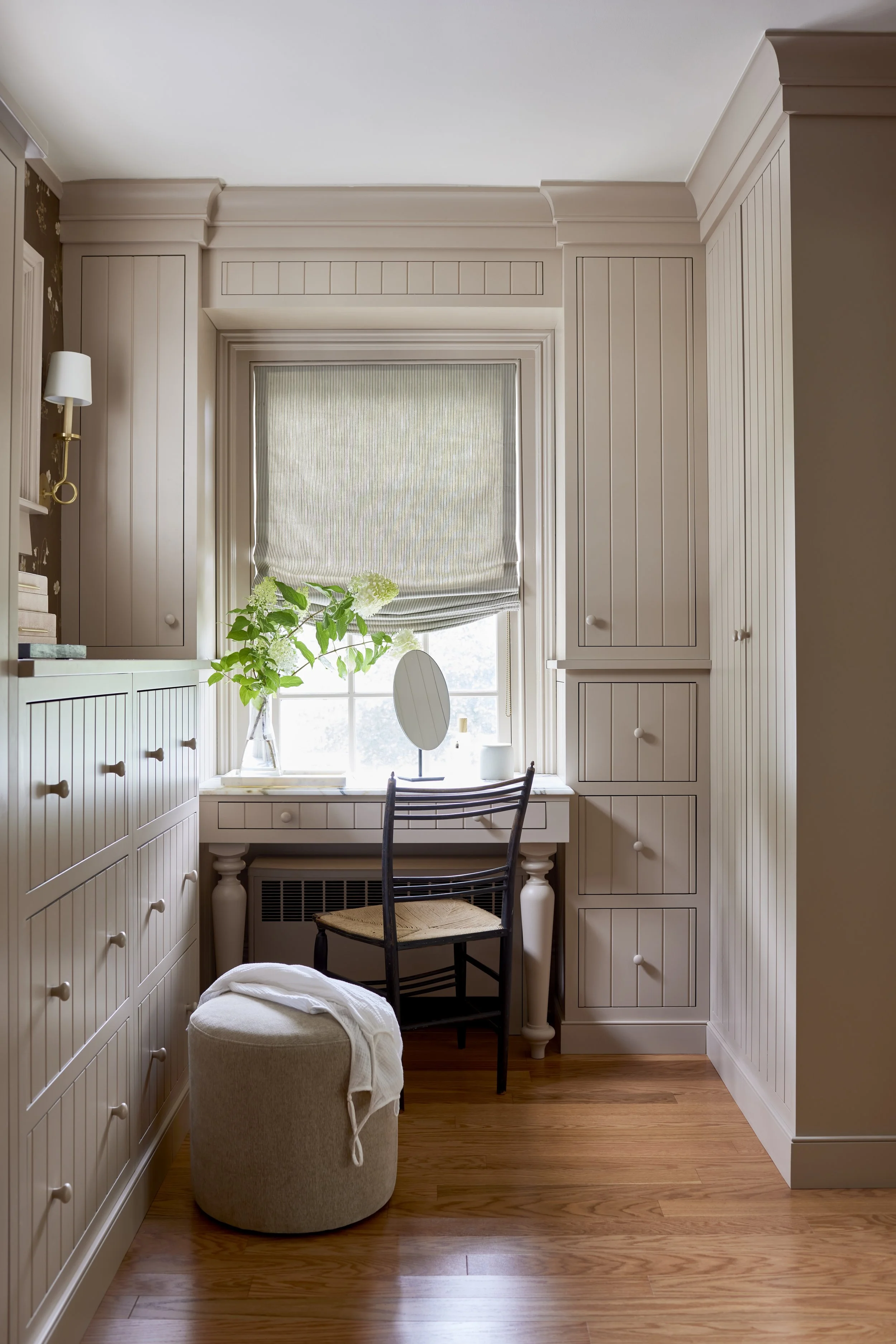 vanity positioned in front of window with custom cabinetry at the sides