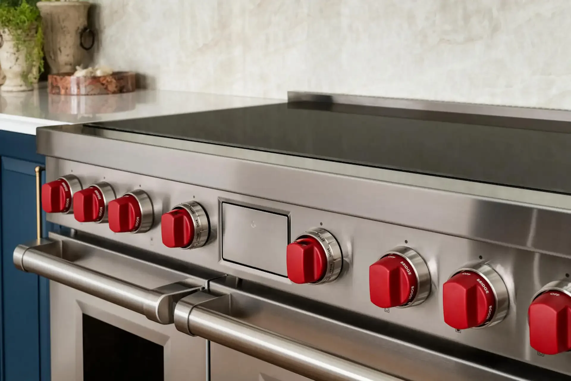 Stainless steel professional range with the red control knobs in a modern kitchen