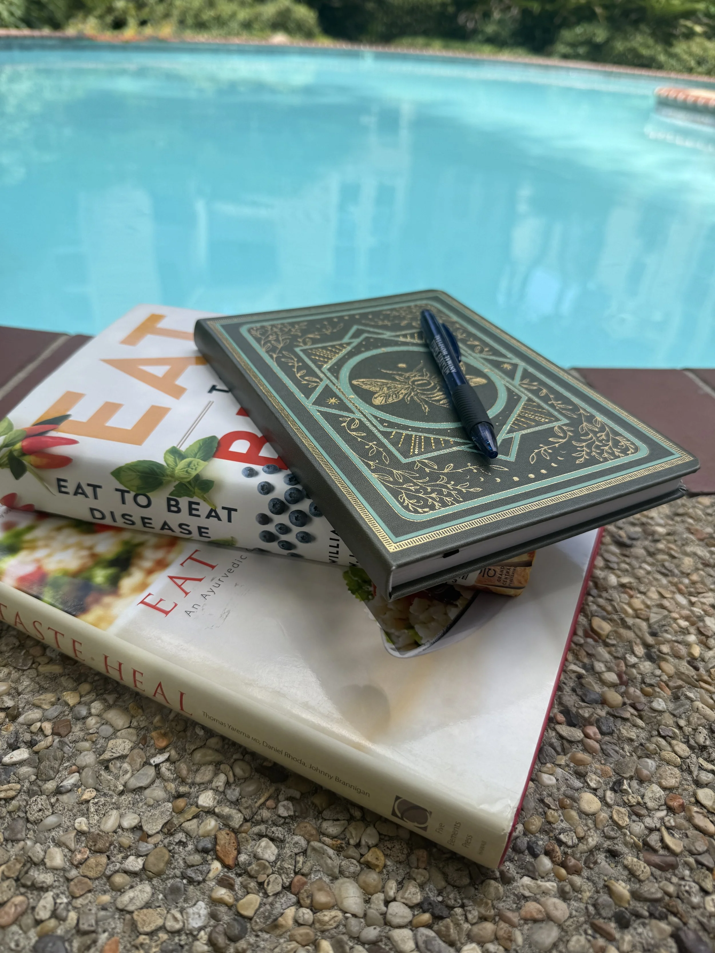 Books by the pool representing rest, balance, and holistic wellness with Whole Health NOLA health coaching in New Orleans.