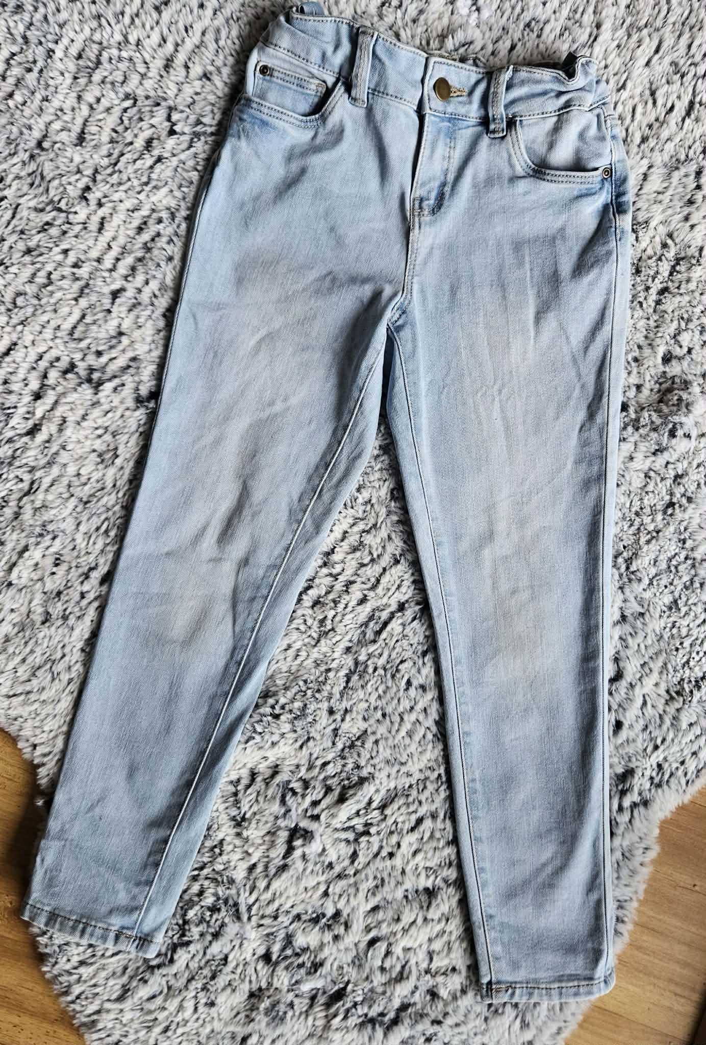 Light blue denim jeans laid flat on a gray shaggy rug.