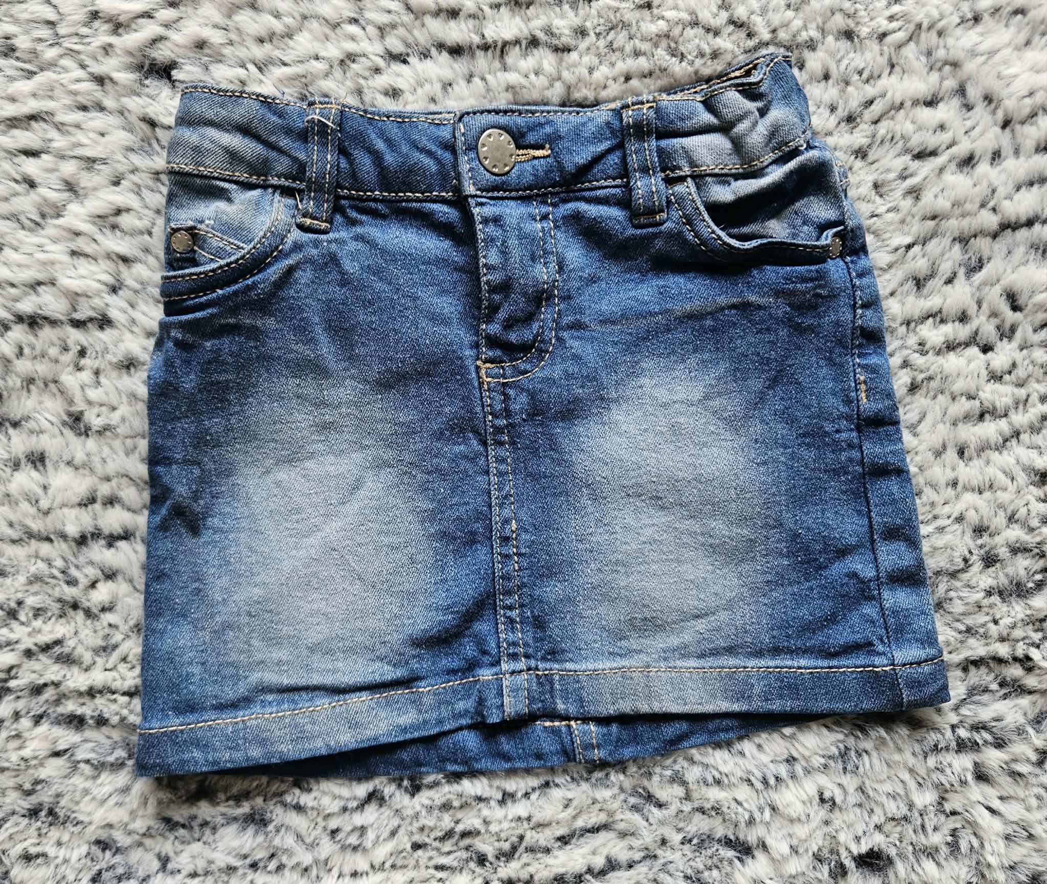 Close-up of a folded pair of blue jeans on a gray, fluffy textured surface.