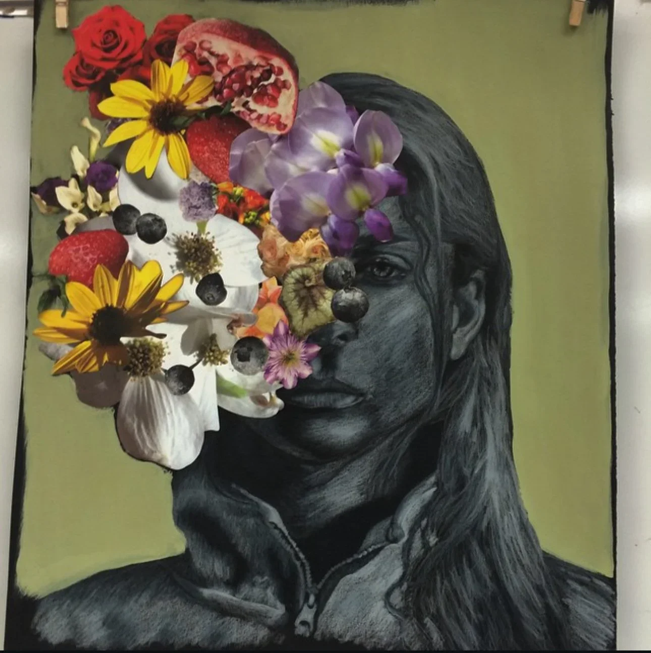 A black and white portrait of a woman with long hair, with a collage of colorful flowers, fruits, and herbs covering the left side of her face and some parts of her head, on a light green background.