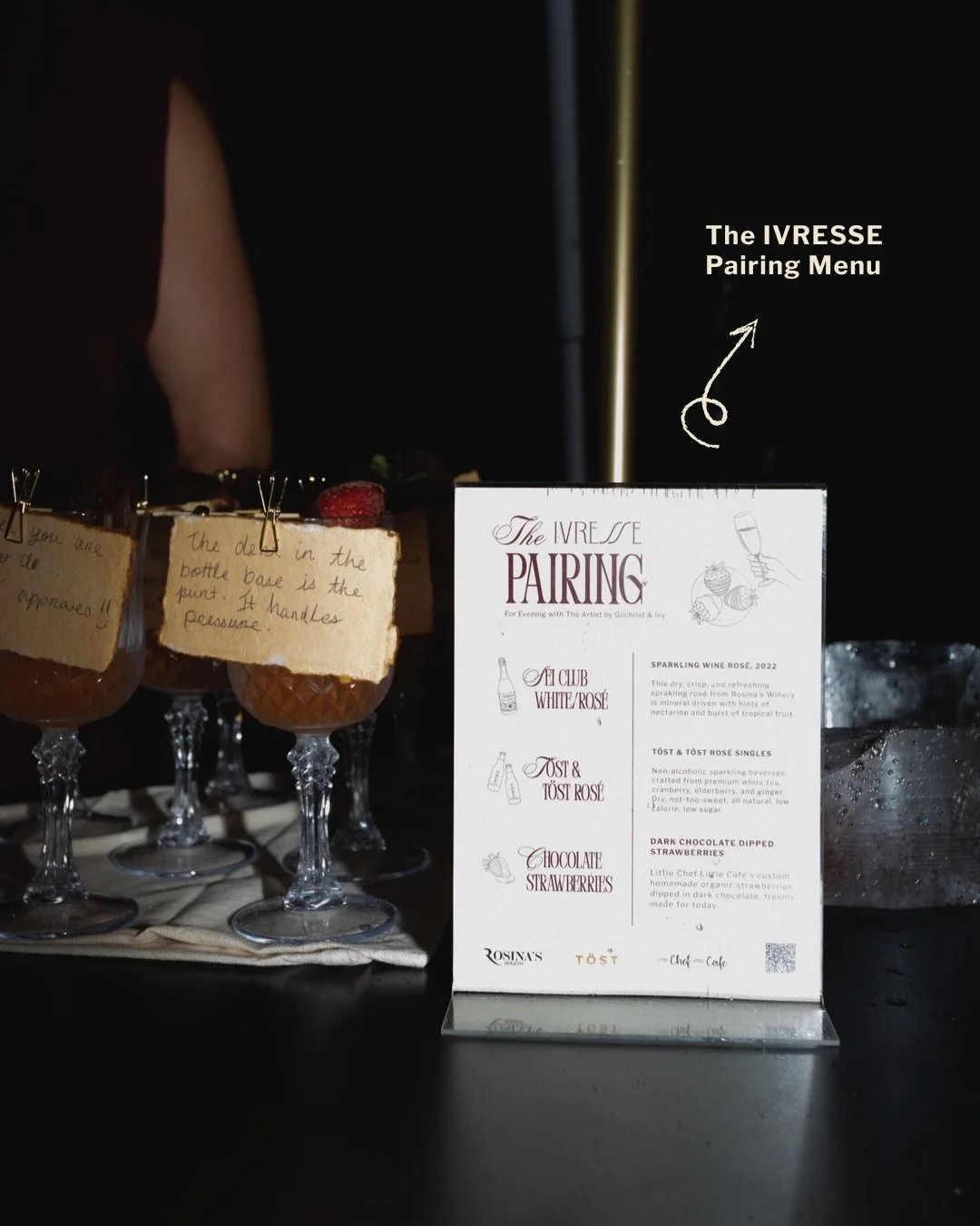 A menu titled 'The Ivresse Pairing' with options for wine and dessert pairings, placed on a black countertop next to glasses with handwritten tasting notes.