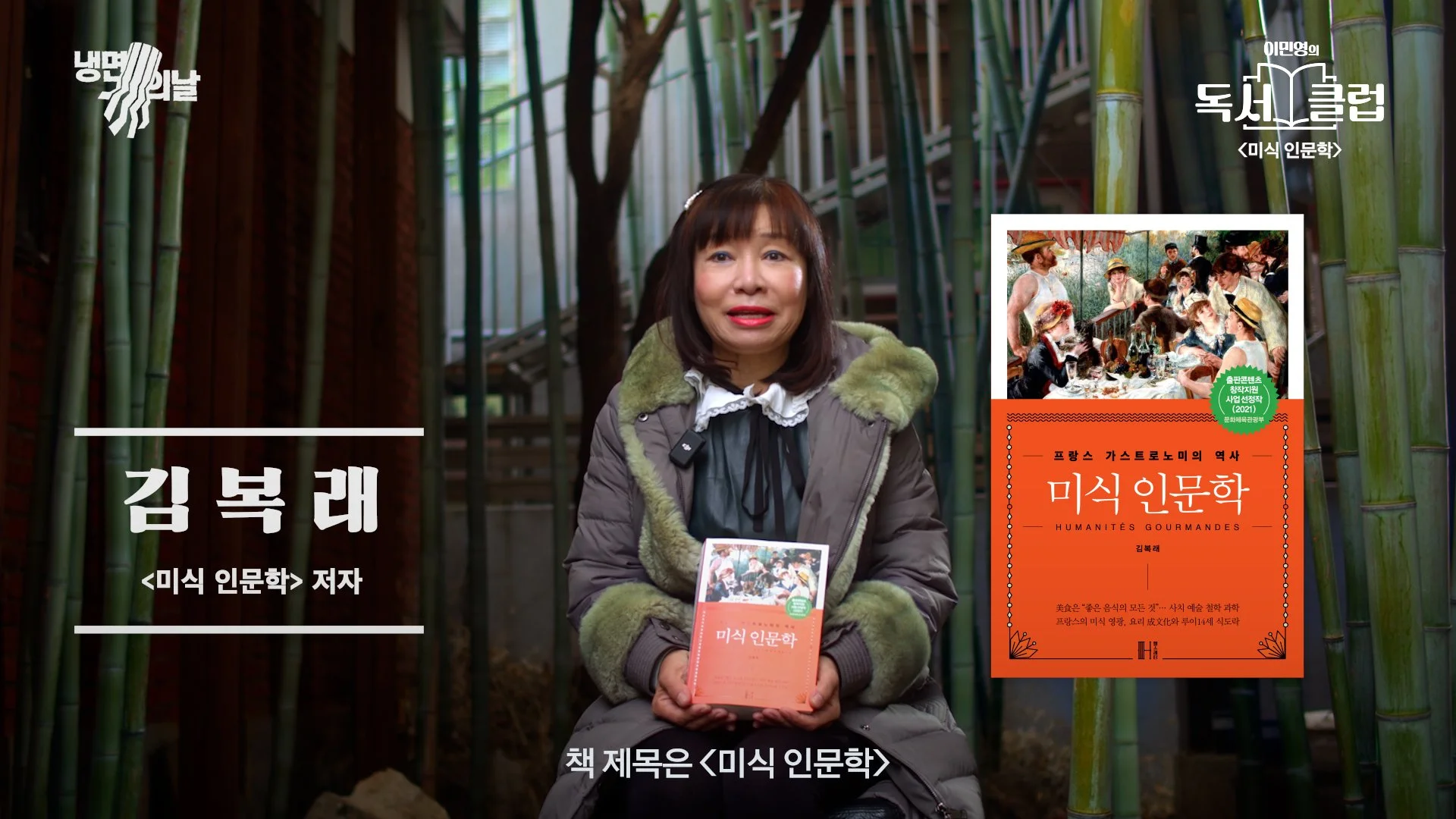 A woman wearing a gray jacket with a green fur-lined hood sitting in front of bamboo stalks, holding a book titled 'Humanités Gourmandes' with a cover illustration of a social gathering. There are Korean and English texts on the image, including her name 'Kim Bok-rae' and the book's title.
