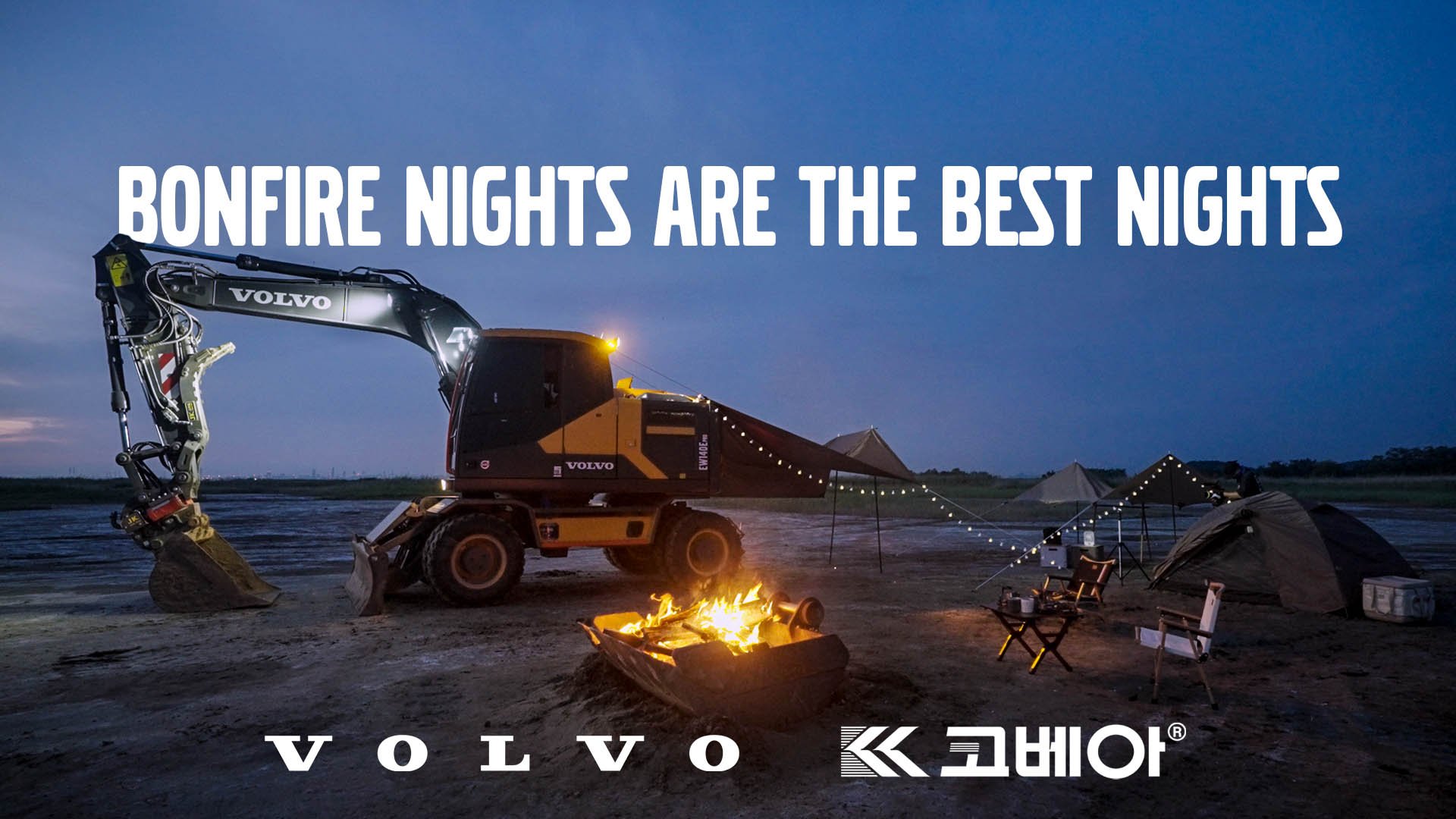 Nighttime outdoor camping scene with a toy bulldozer on a sandy area, campfire, tents, string lights, and camping chairs under a dark sky, with the text 'Bonfire nights are the best nights' and Volvo logo.