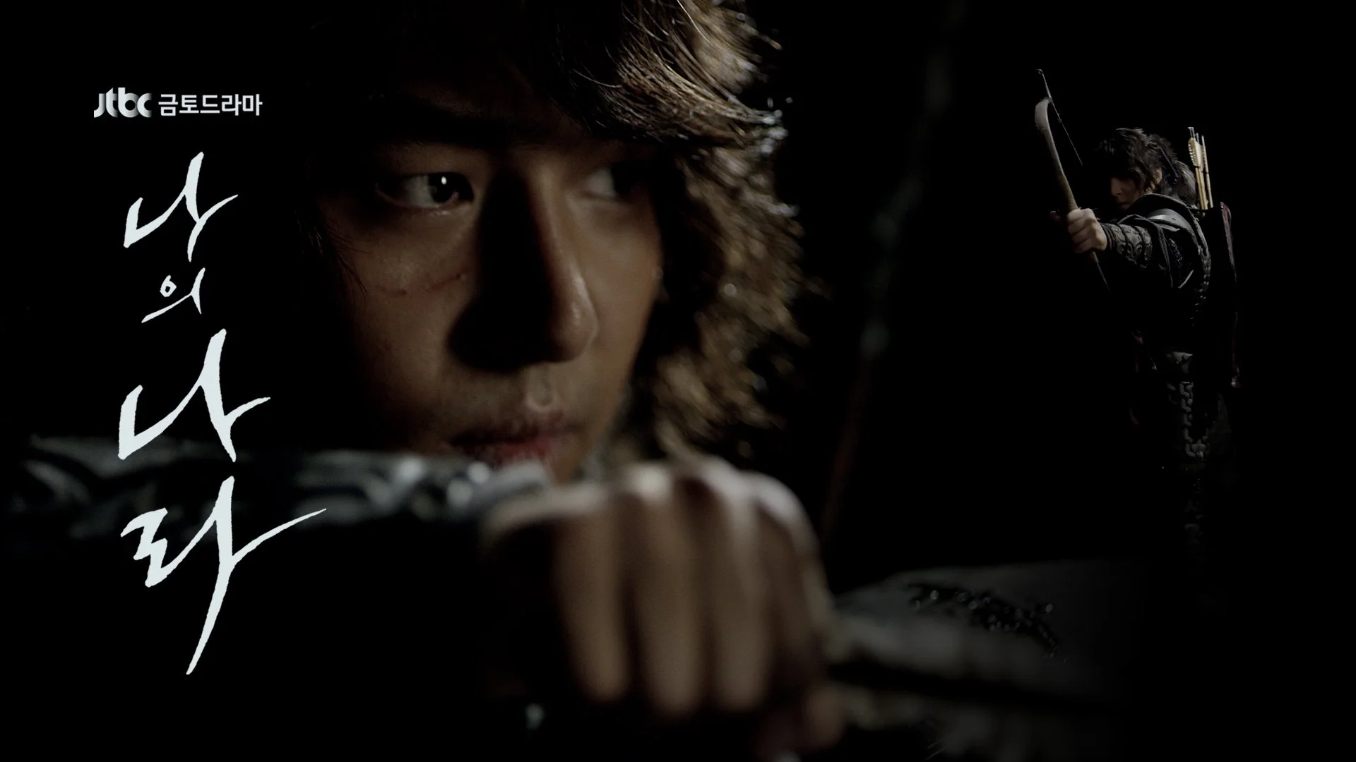 A close-up of a man with long hair focusing intently, aiming a bow and arrow, with a second person in the background holding a bow.