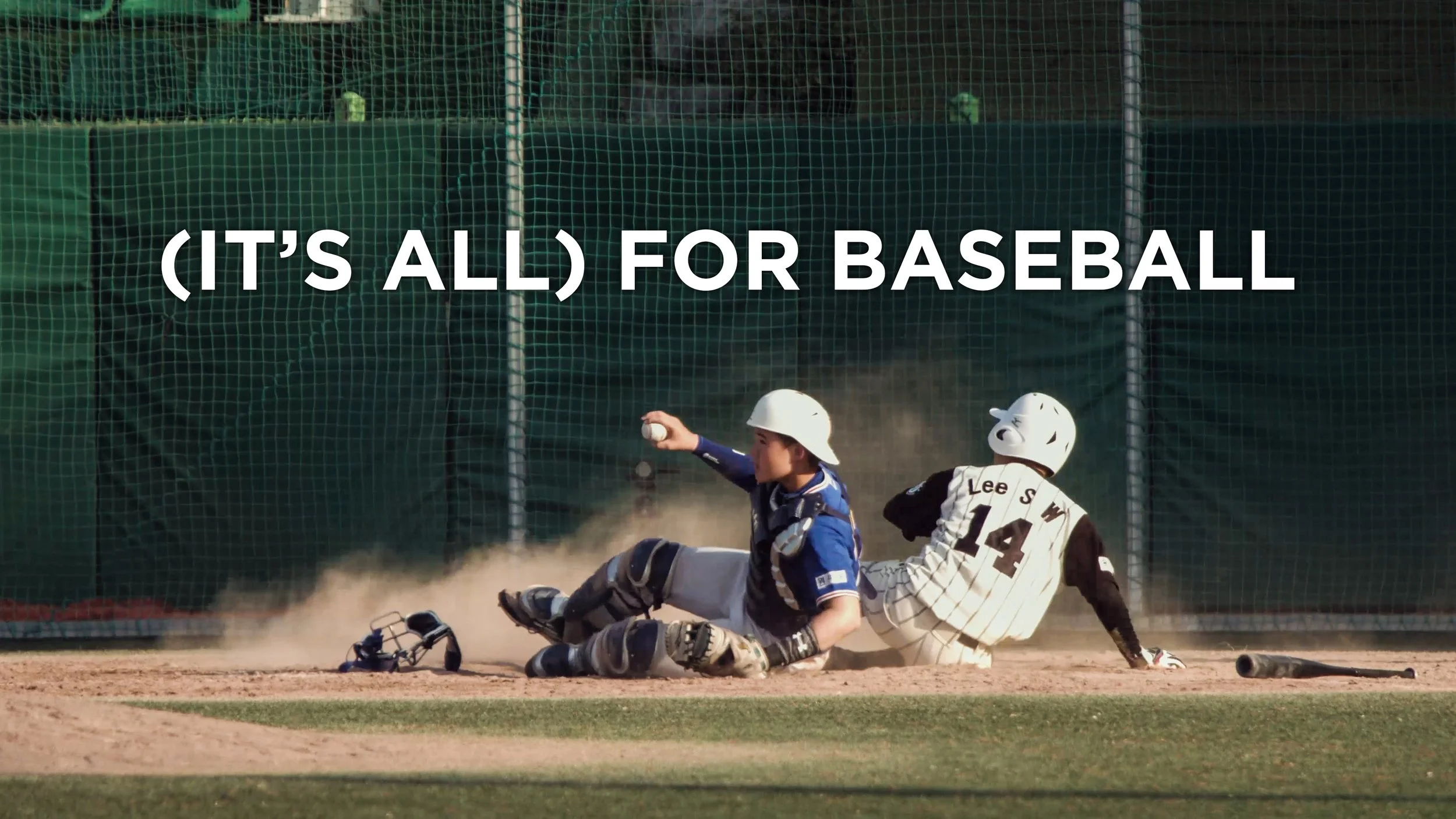 Two young baseball players fall to the ground after a collision at home plate during a game, with the batter sliding and the catcher attempting to catch the ball.