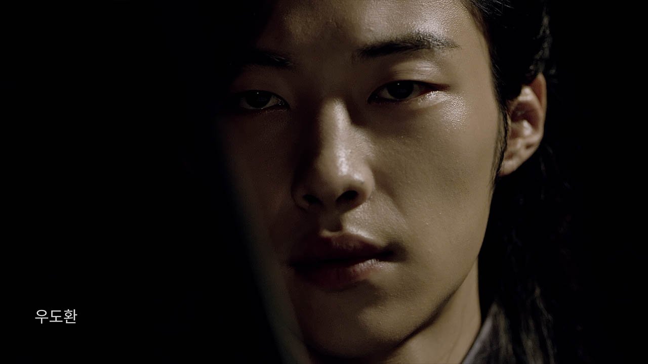 Close-up of a young man's face with a serious expression, half of the face in shadow.