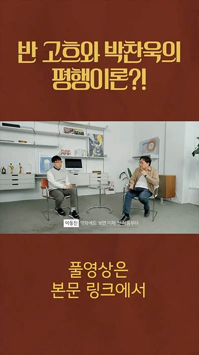 Two men sitting and talking in a modern office or studio setting. One is wearing a white shirt and gray pants, and the other is wearing a tan jacket and dark pants. There are shelves with decorative items and a computer in the background. Text in Korean is displayed at the top and bottom of the image.