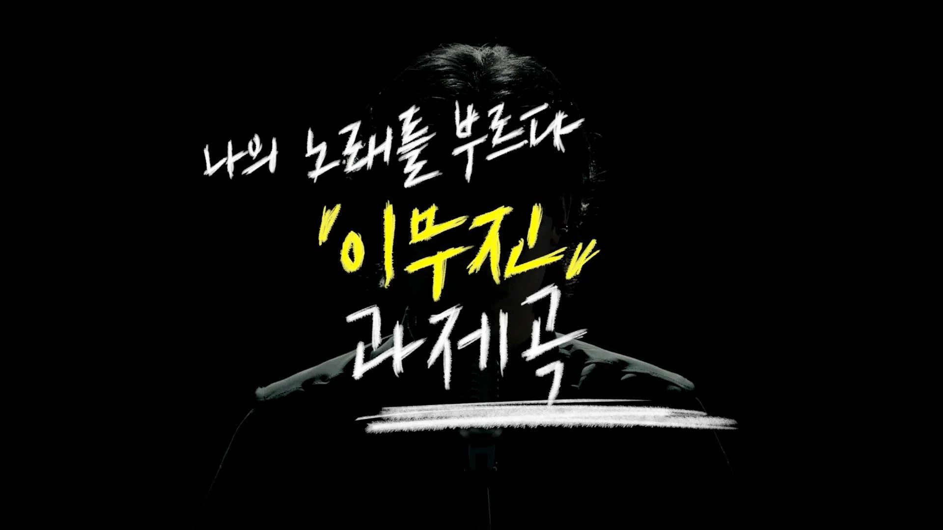 A person with dyed hair and a patterned shirt is holding a sign with Korean text written in white and yellow. The background is black.