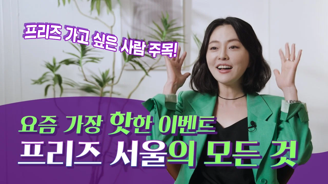 A woman with shoulder-length black hair wearing a green blazer, speaking and gesturing with her hands in a room with white walls and a potted plant in the background. Korean text overlaid on the image.
