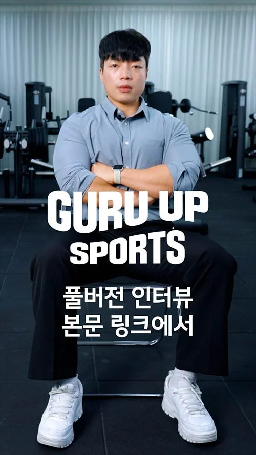 Man sitting on a chair in a gym, wearing a gray shirt and white sneakers, with gym equipment in the background, with text overlay reading 'GURU UP SPORTS' and Korean text.
