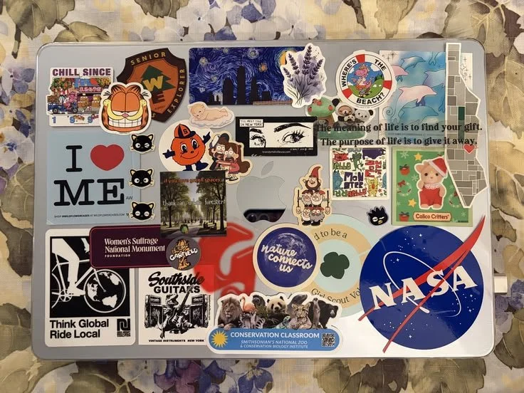 A collection of various stickers on a laptop, including NASA, wildlife, environmental, travel, and social themes.