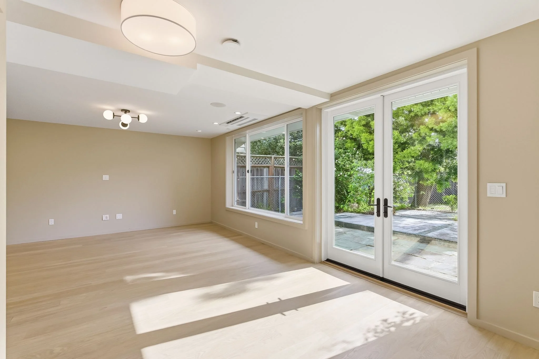 Living and dining area with French doors to a patio, hardwood floors, and recessed lighting
