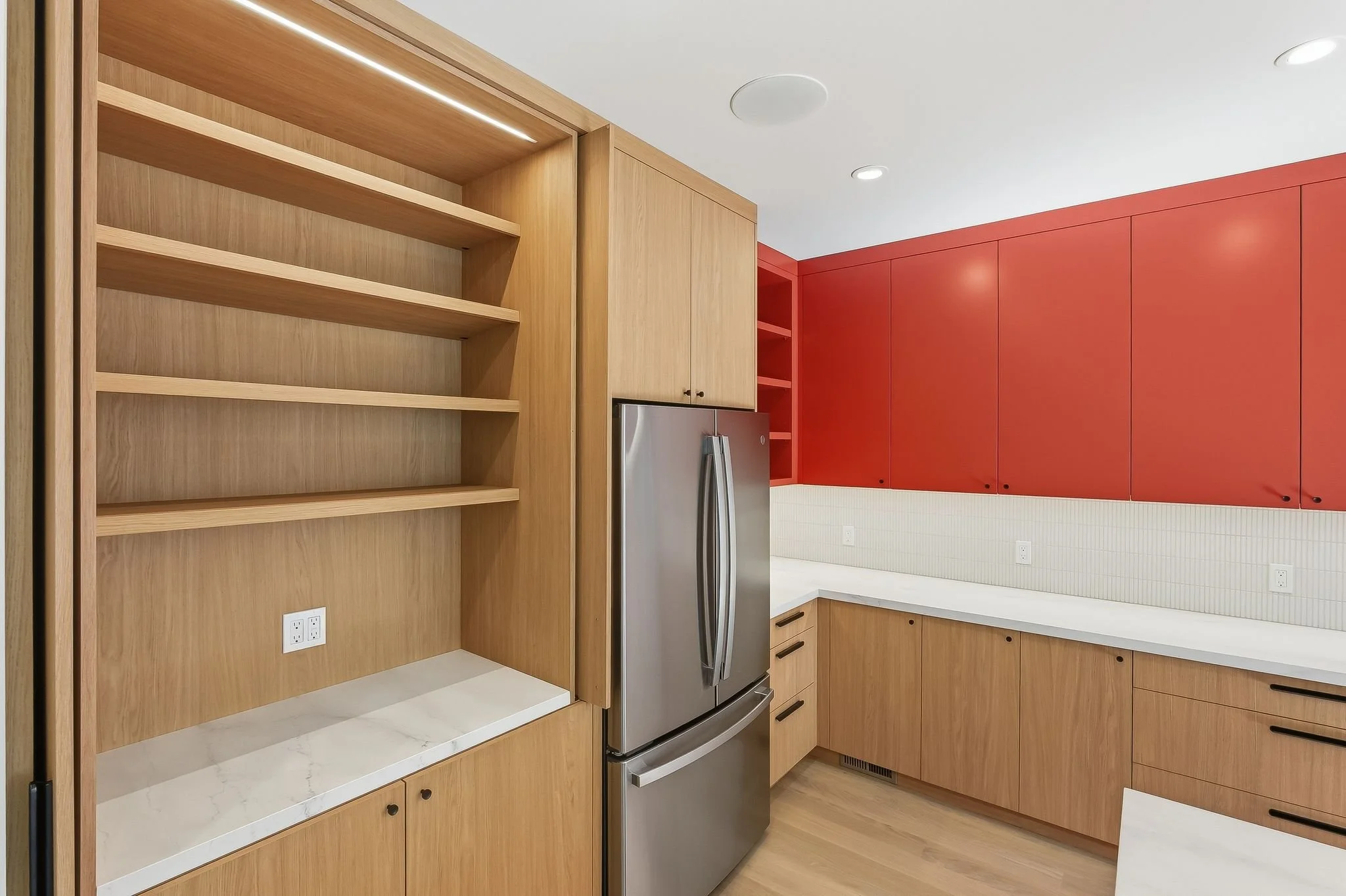 Kitchen pantry wall with wood open shelving, stainless steel refrigerator, and orange accent cabinetry