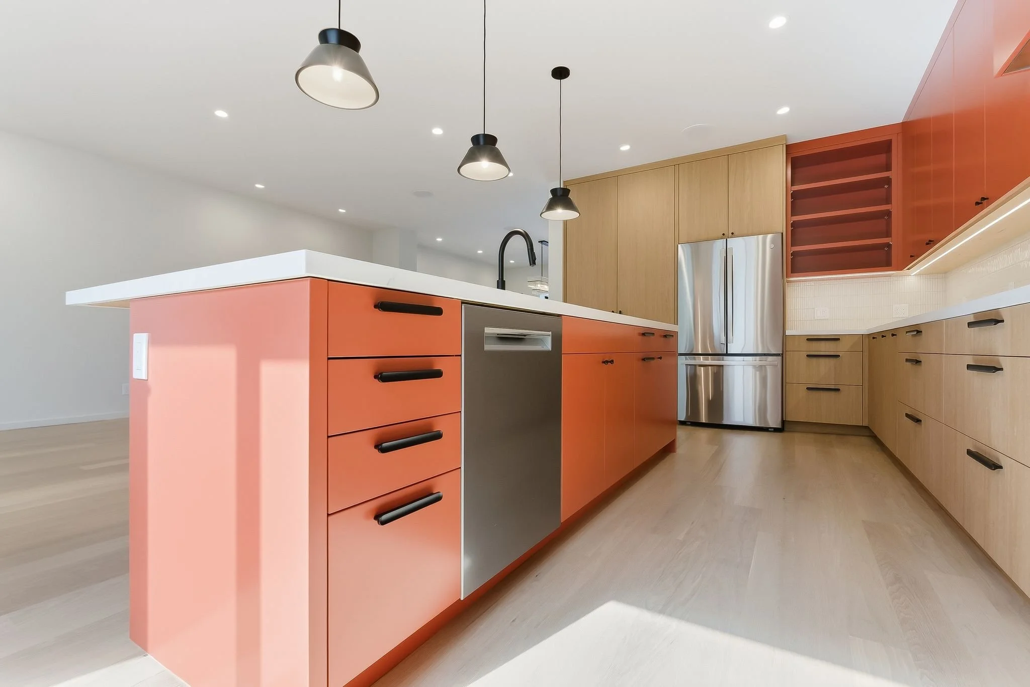 Kitchen with orange island, wood cabinetry, open shelving, and stainless steel refrigerator