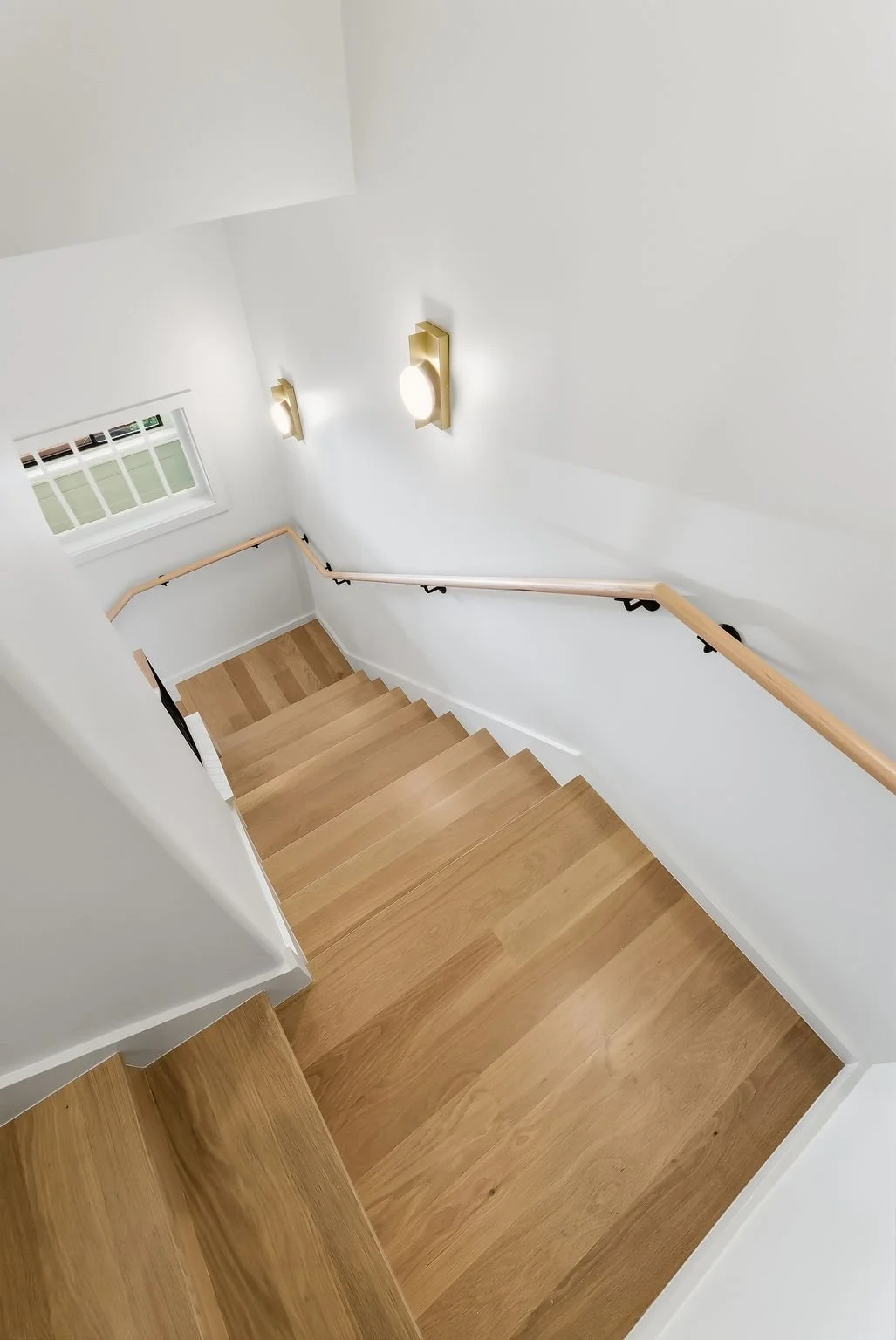 White staircase with wood treads and wall-mounted sconces