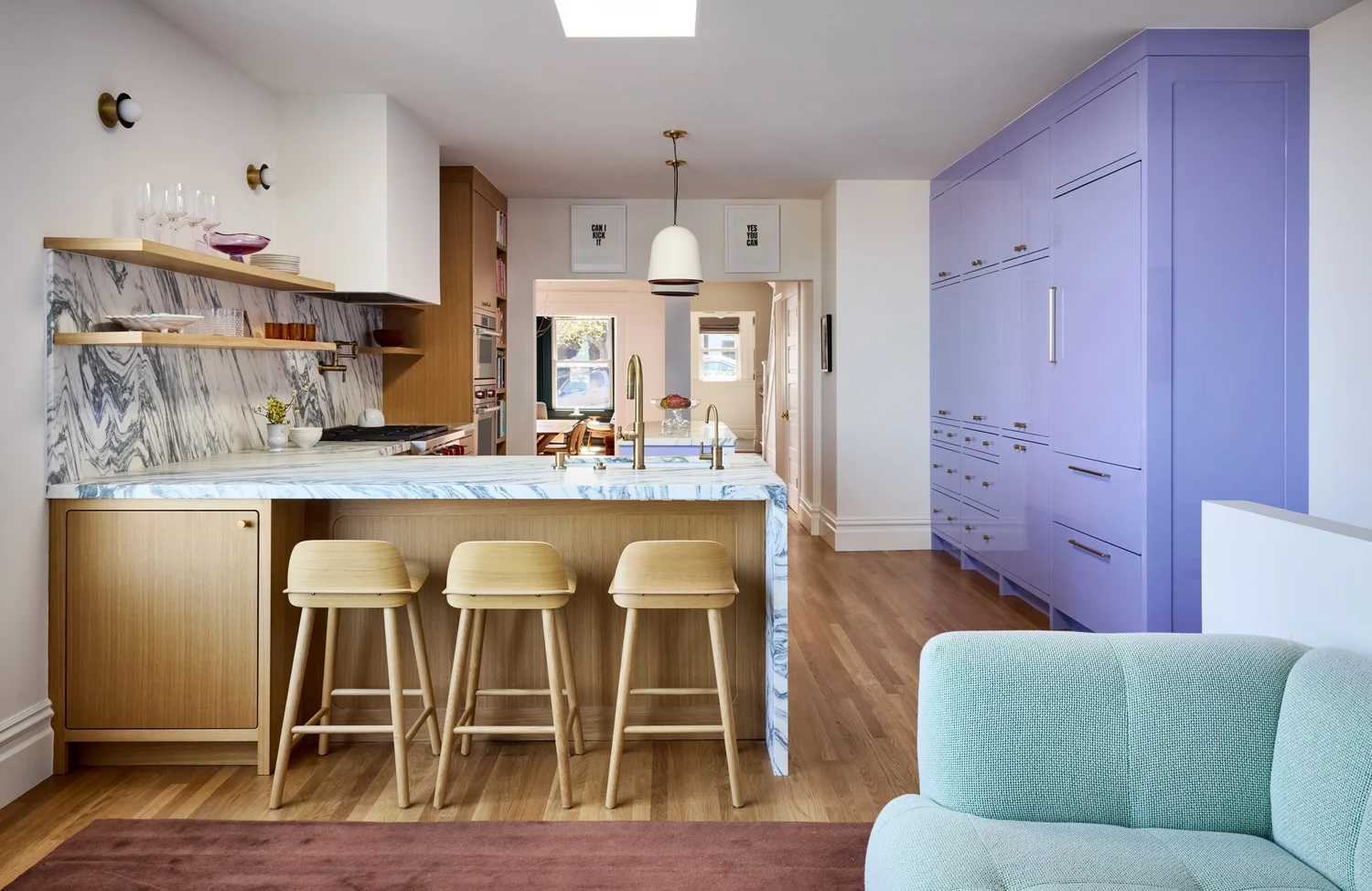 After — renovated kitchen with light-wood island, bar seating, and purple cabinetry