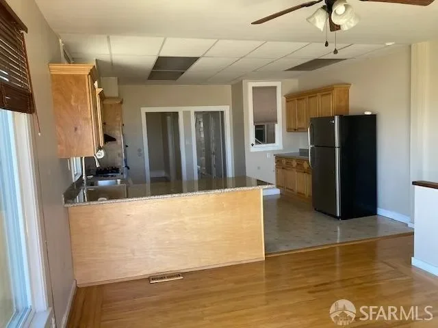 Before — original kitchen with dated cabinets and worn wood floor