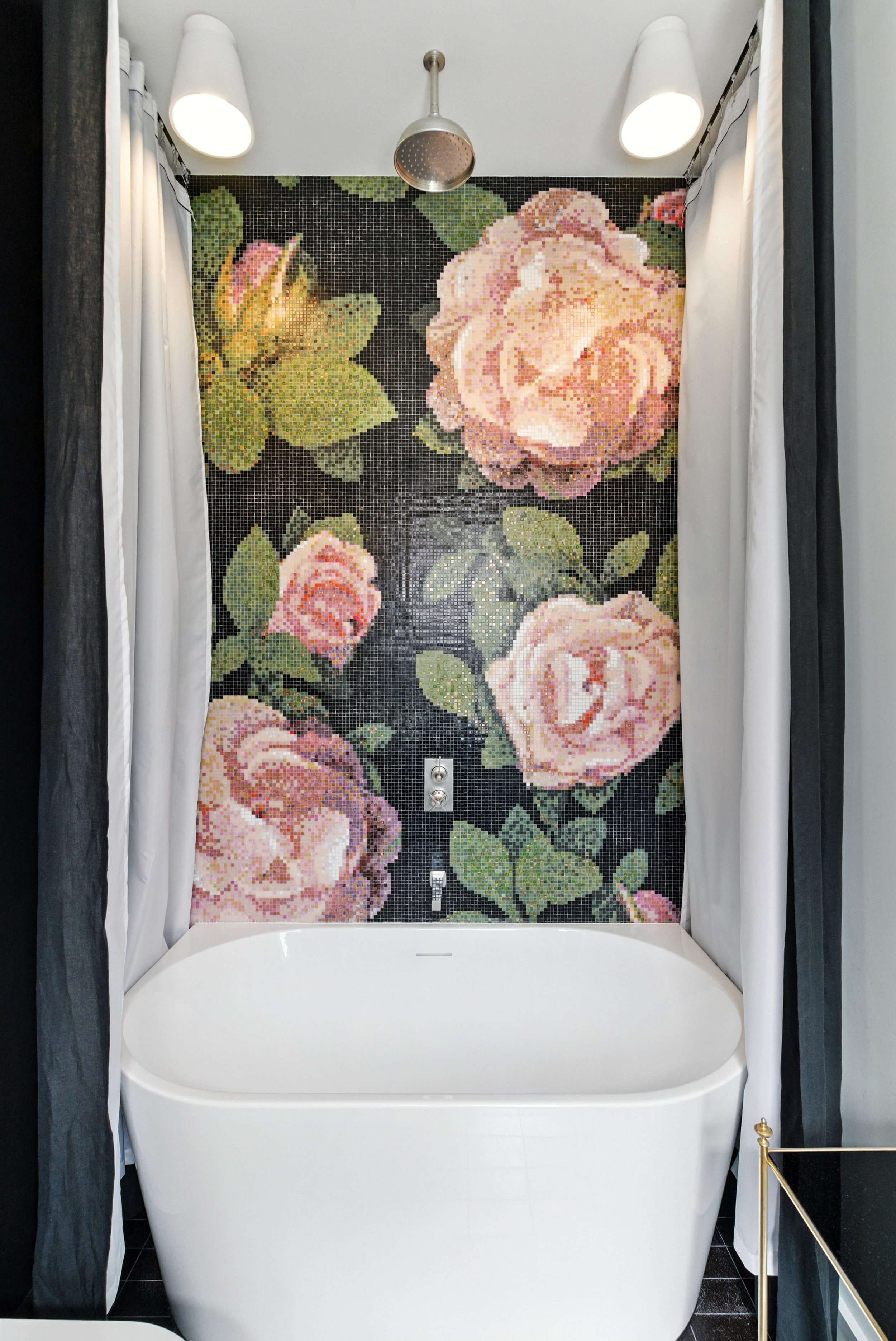 Bathroom with freestanding white soaking tub and dramatic pink rose floral mosaic tile feature wall