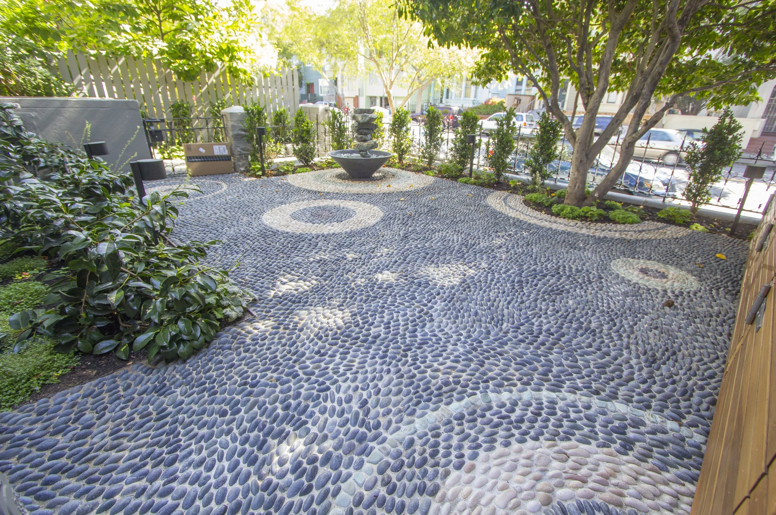 Landscaped courtyard with pebble mosaic paving, planted borders, and a small tree