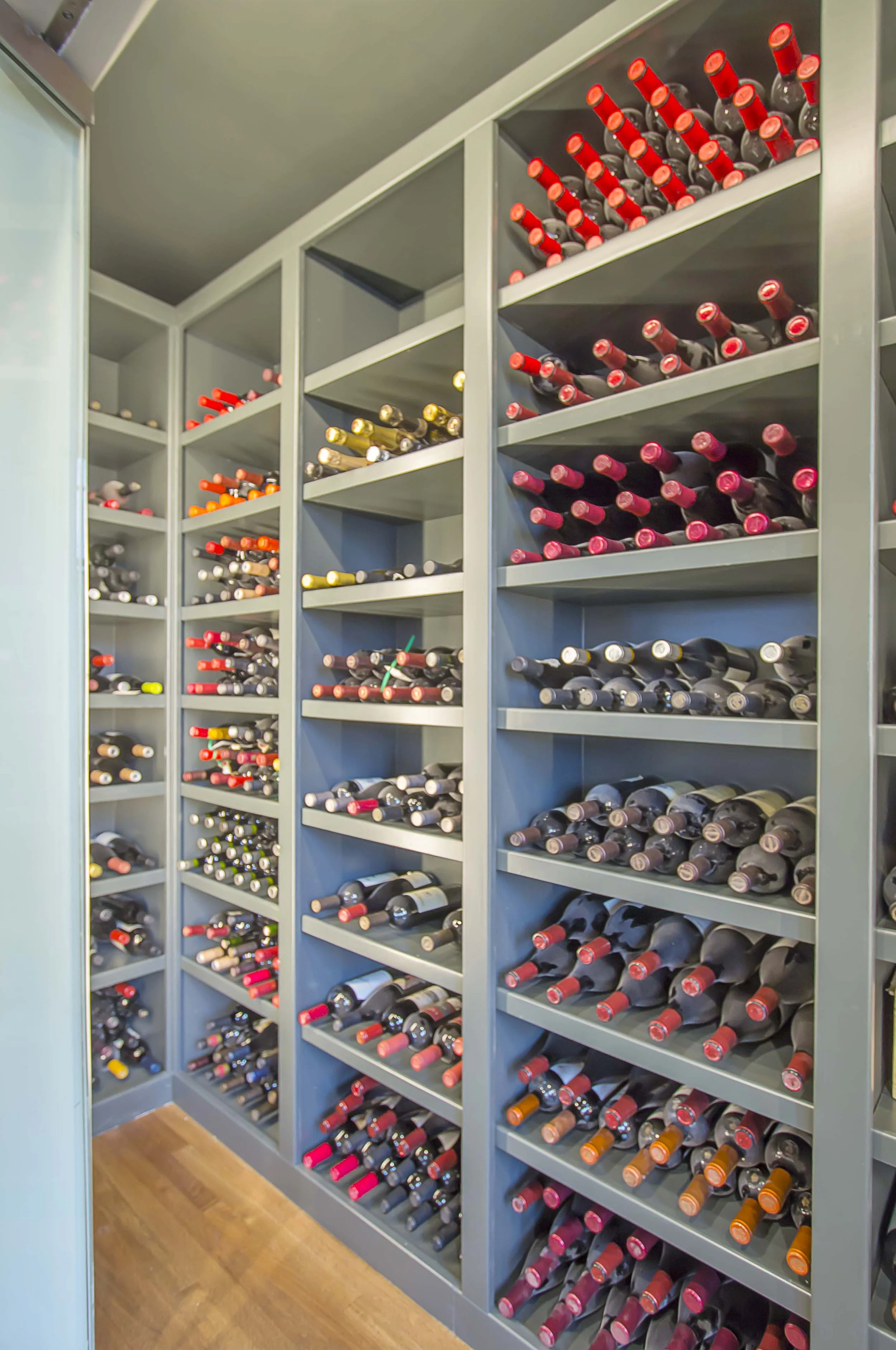 Built-in wine storage shelving filled with wine bottles on angled wood racks