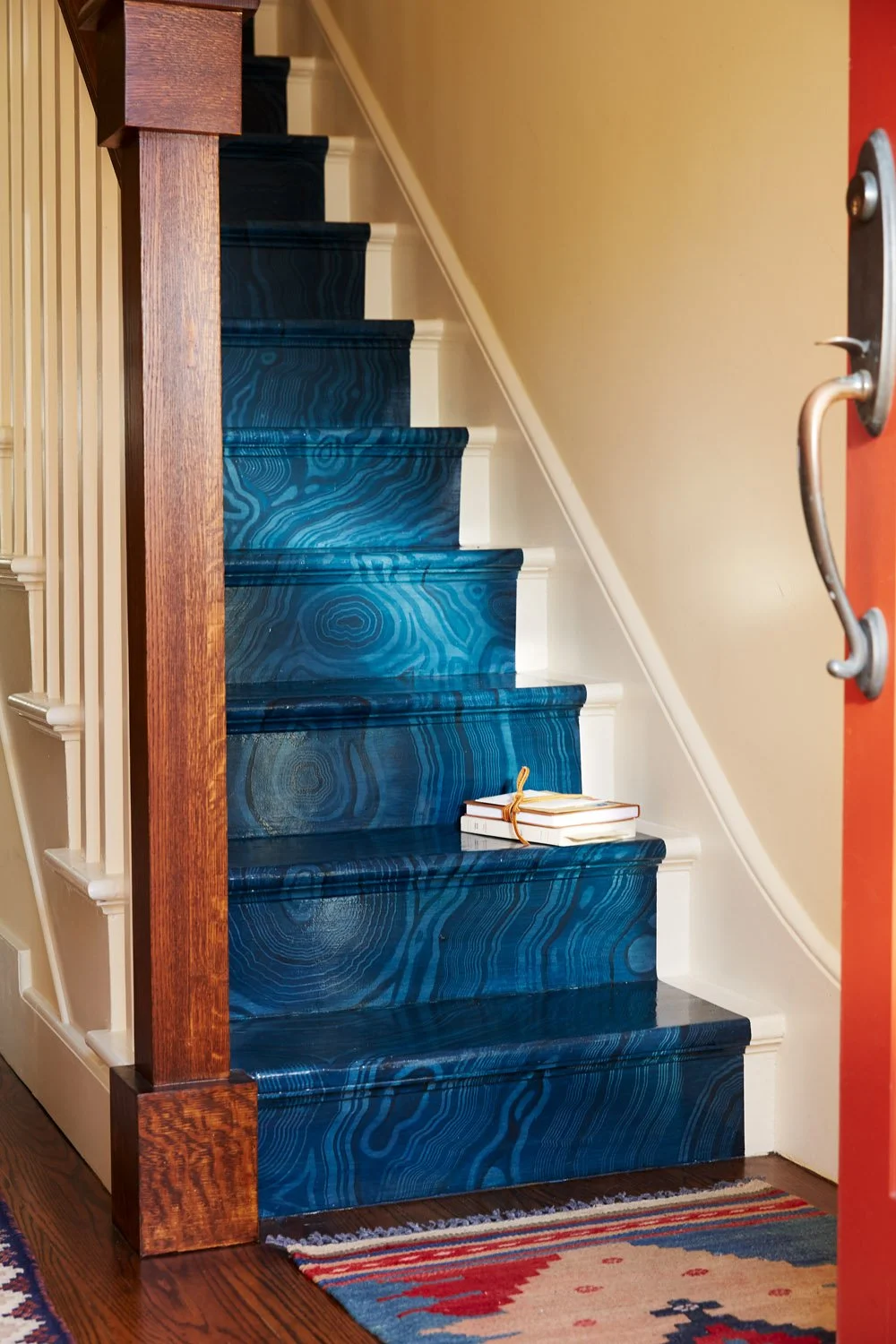 Staircase with blue-painted risers, white balusters, and a wood newel post