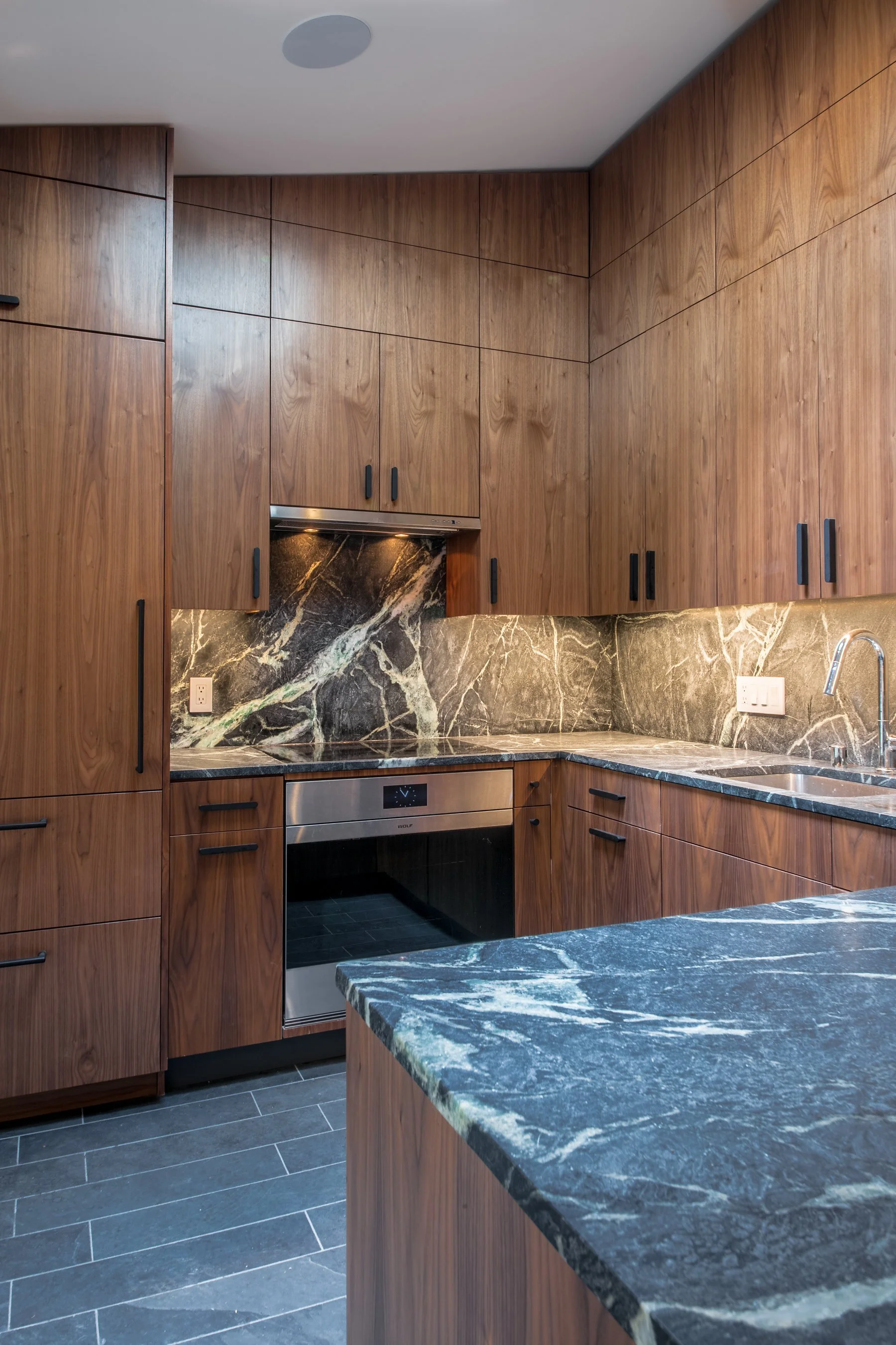 Close view of the dramatic veined marble backsplash and countertop above the Wolf oven and cooktop