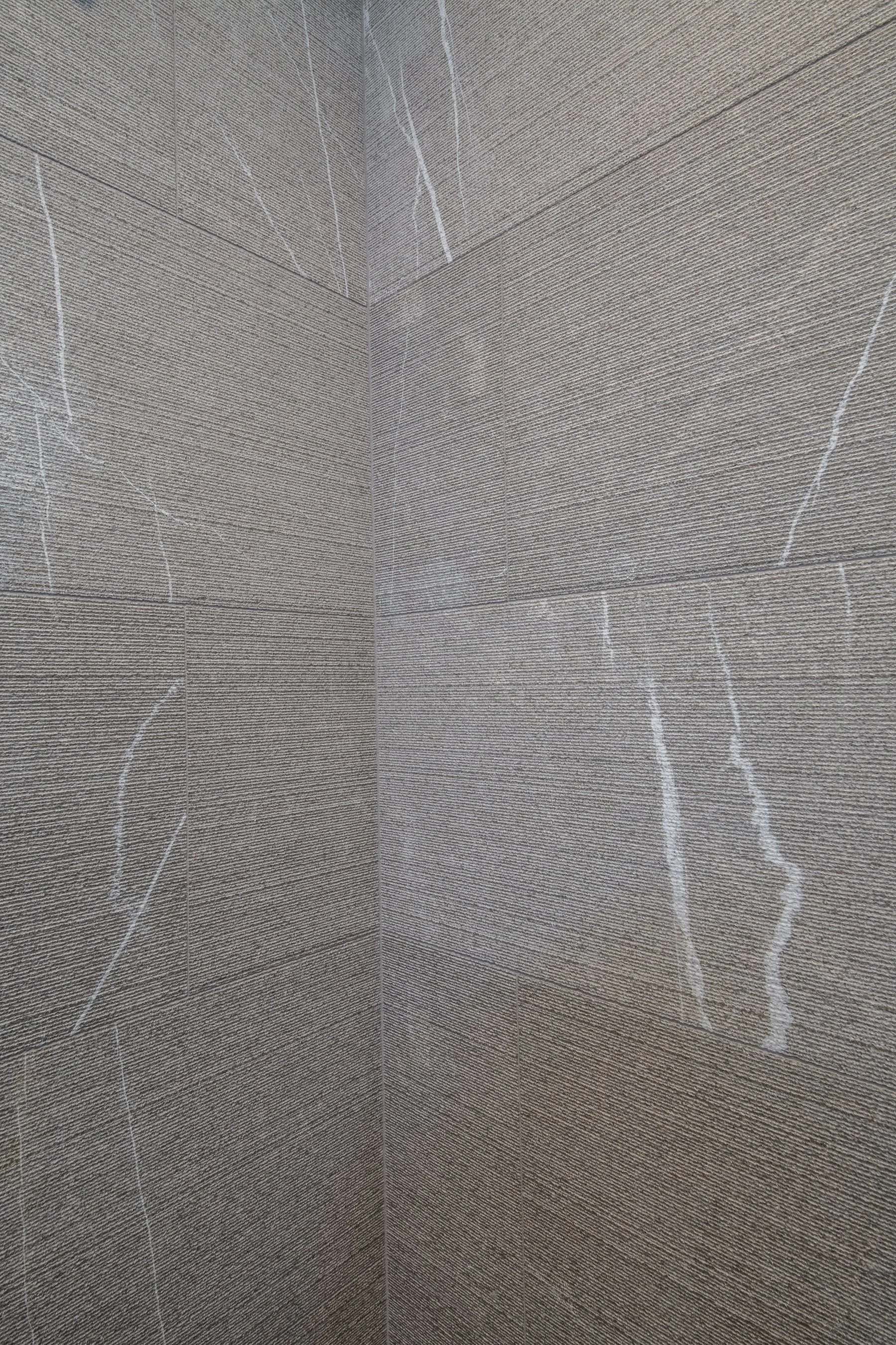 Detail of the linear-cut grey stone tile with white veining meeting at the shower corner