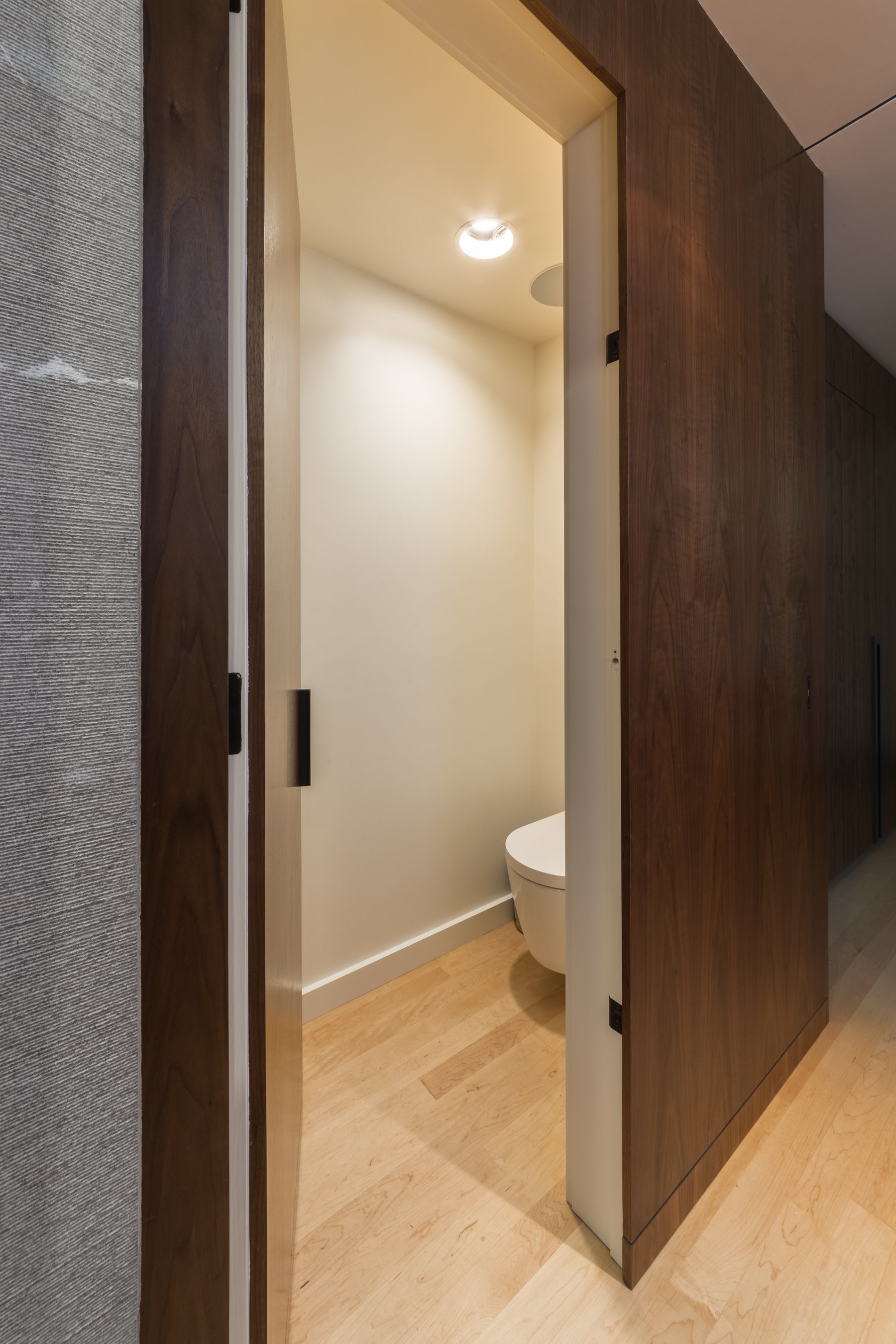Walnut pocket door open to the separate water closet off the grey bathroom