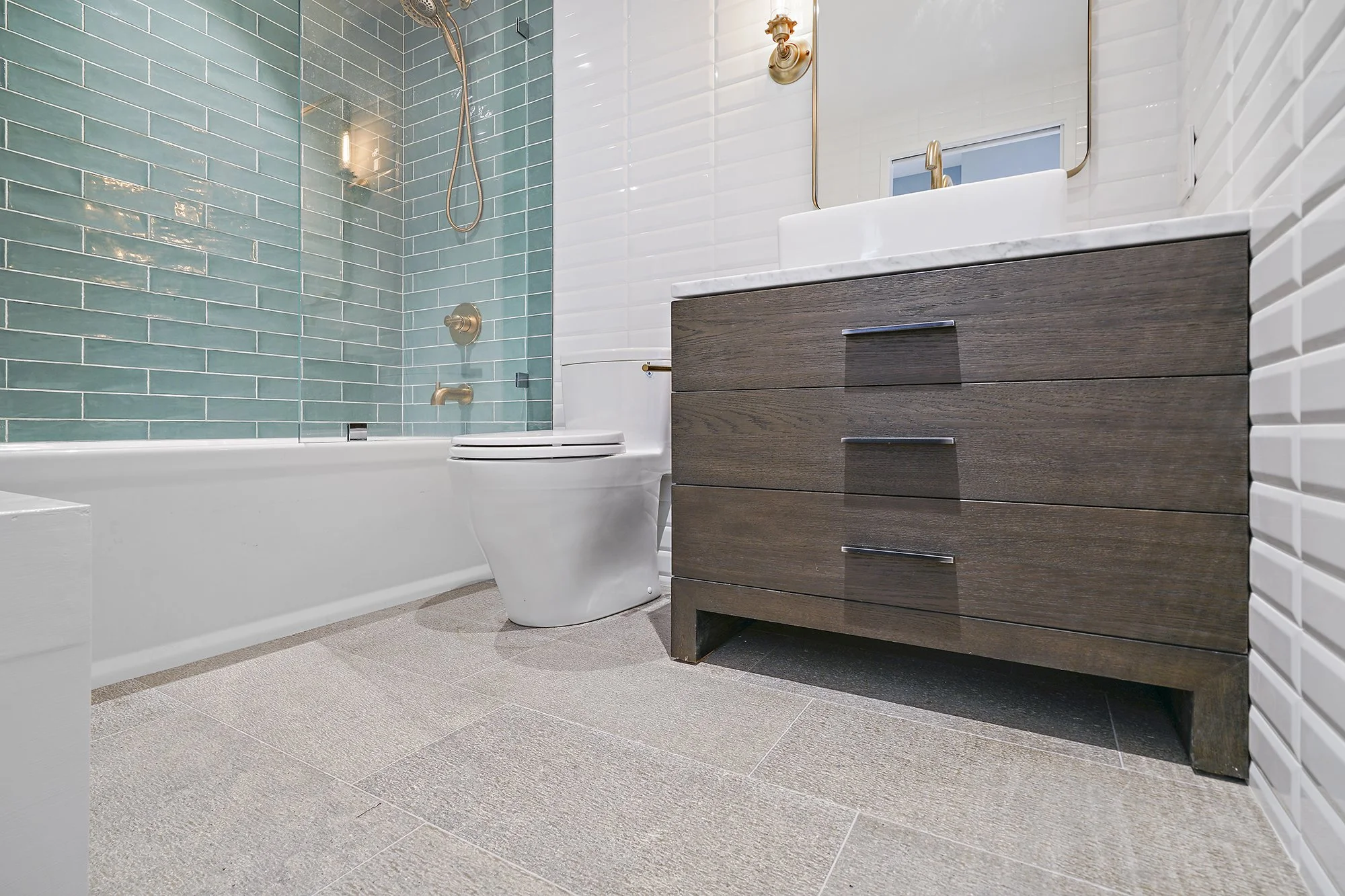Bathroom with a green glass-tile shower, a dark wood vanity with brass pulls, a tub, and a gray tile floor